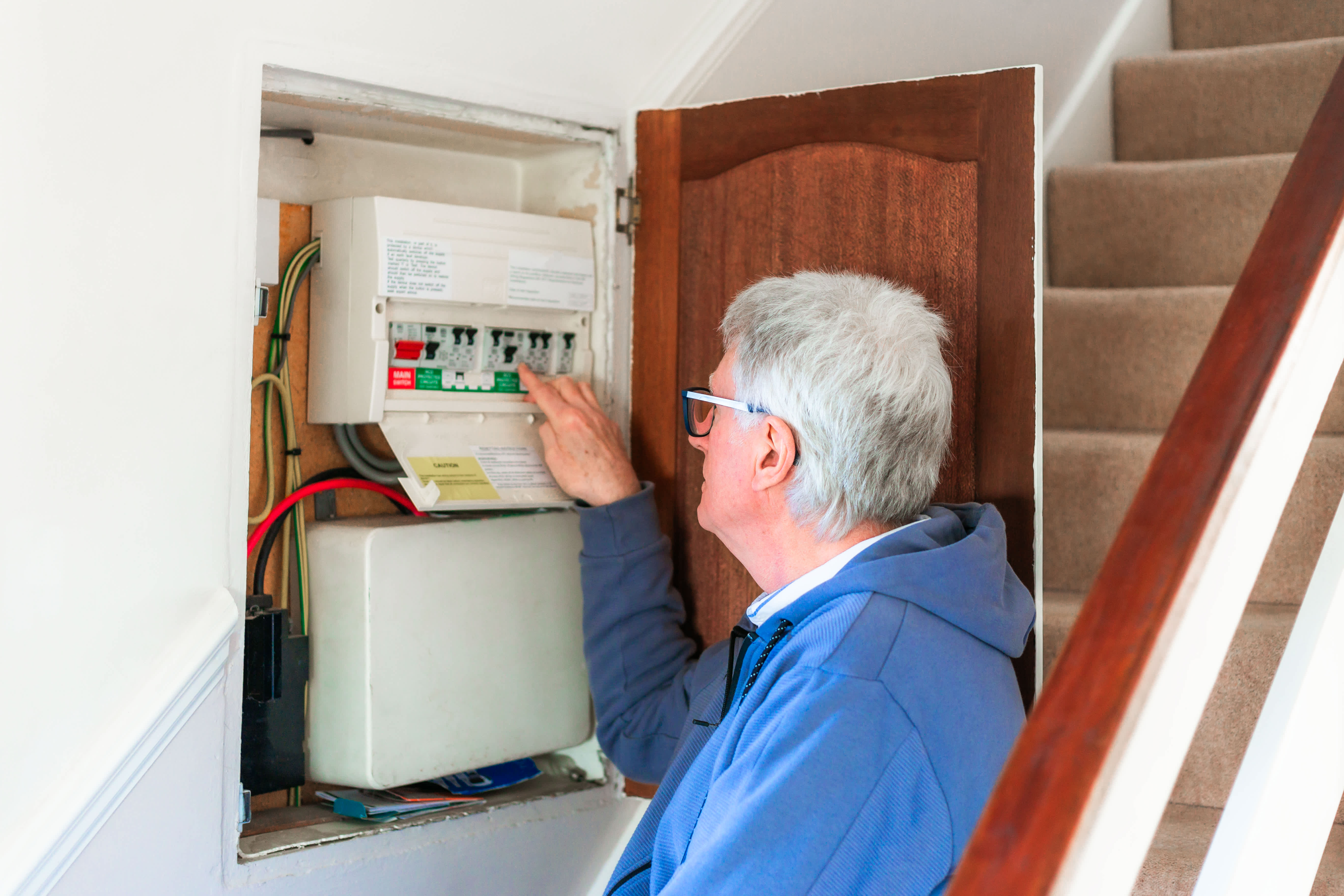 man looking at electrical panel in cabinet