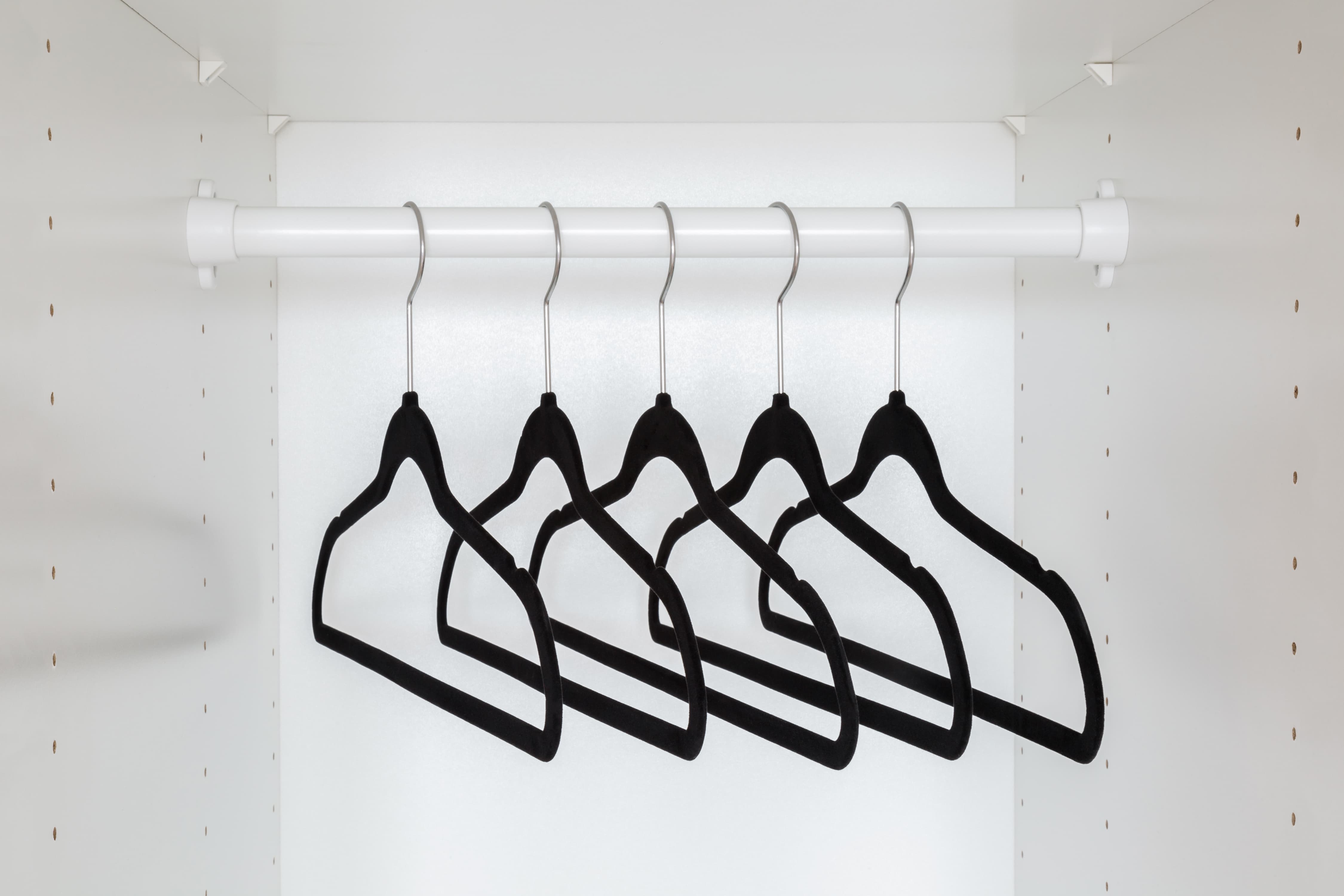 Dark black velvet empty hangers without clothes on rail
