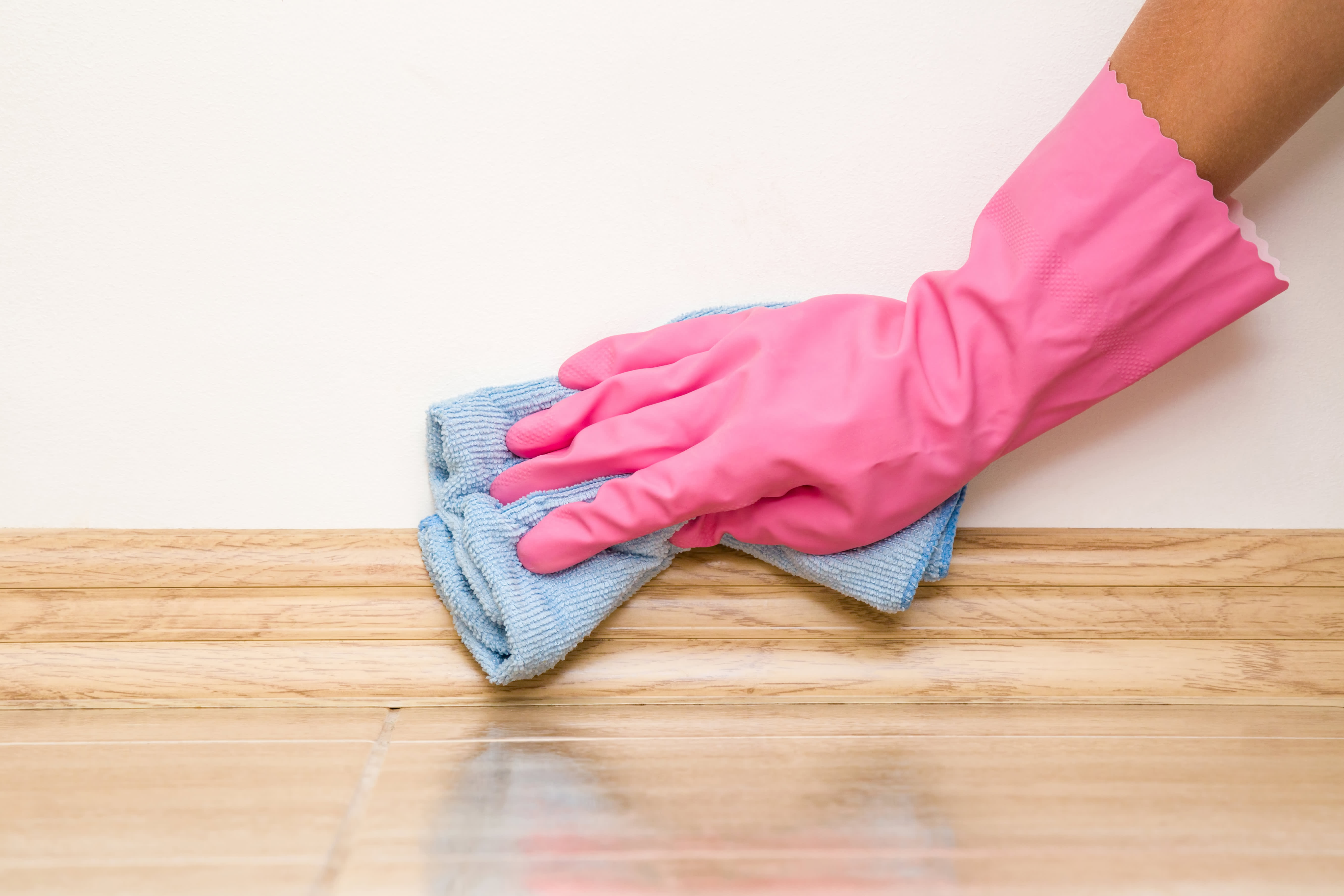 A person cleaning a baseboard
