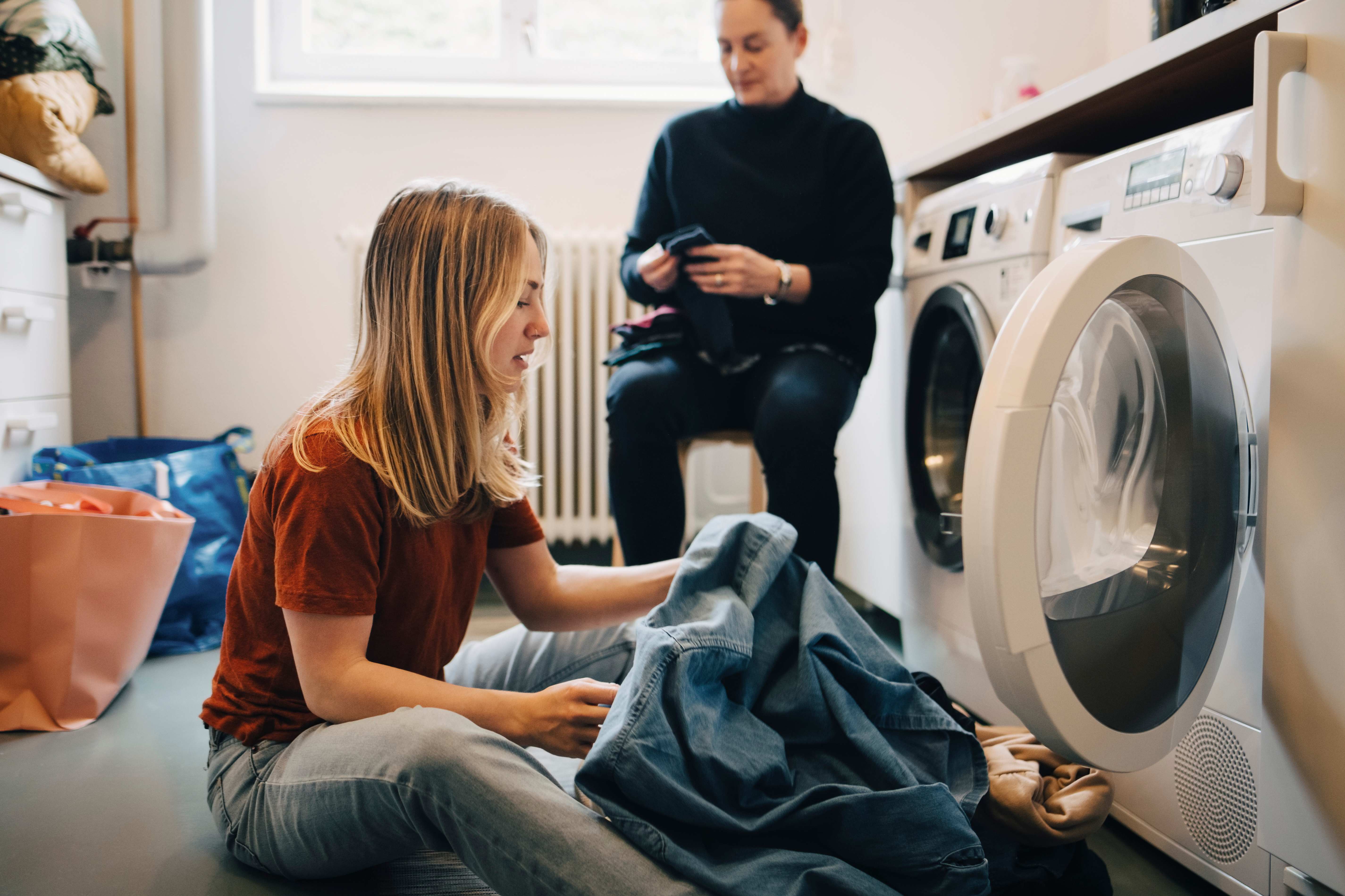 A young woman putting clothes into the washing machine