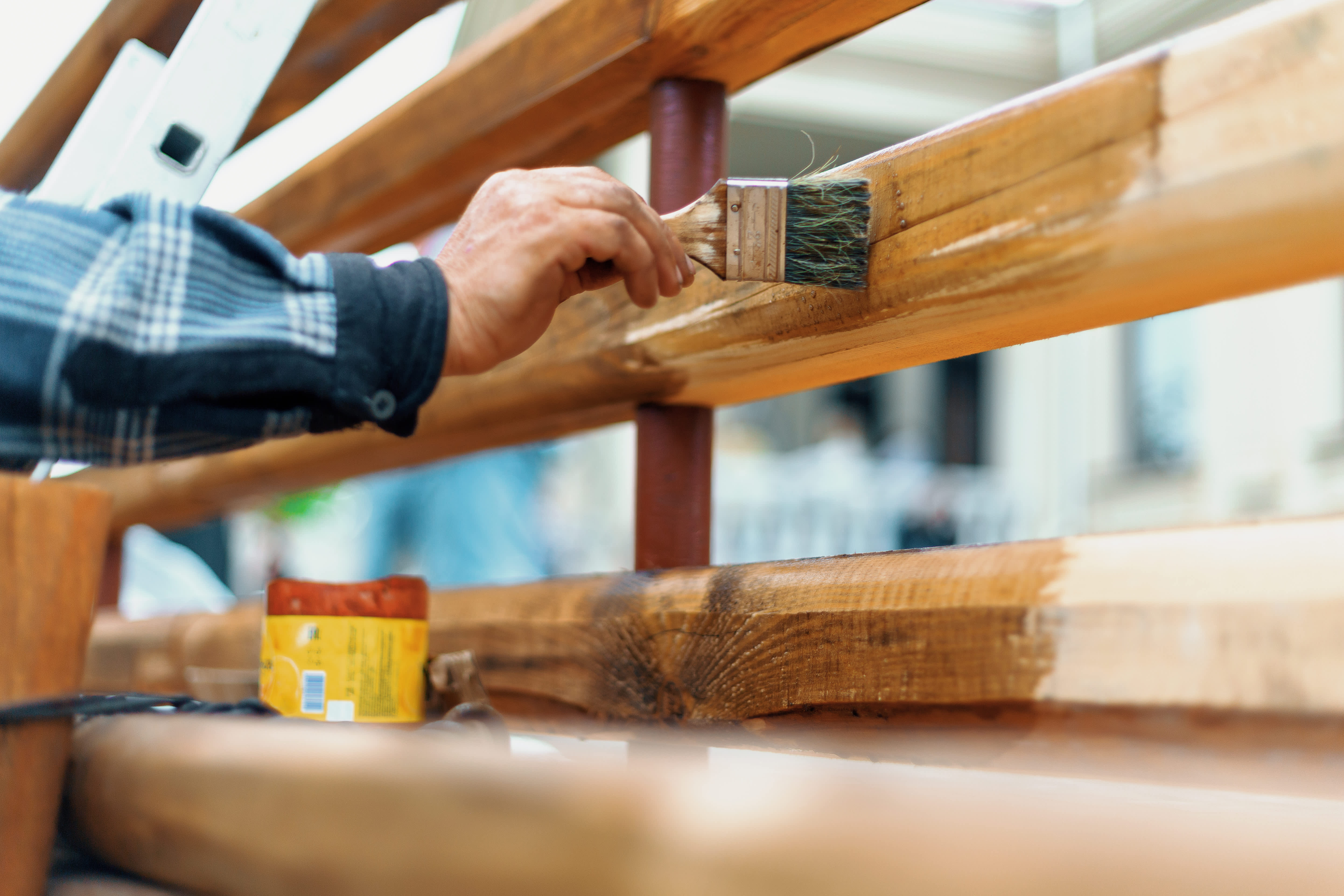 Carpenter varnishing a new wooden fence