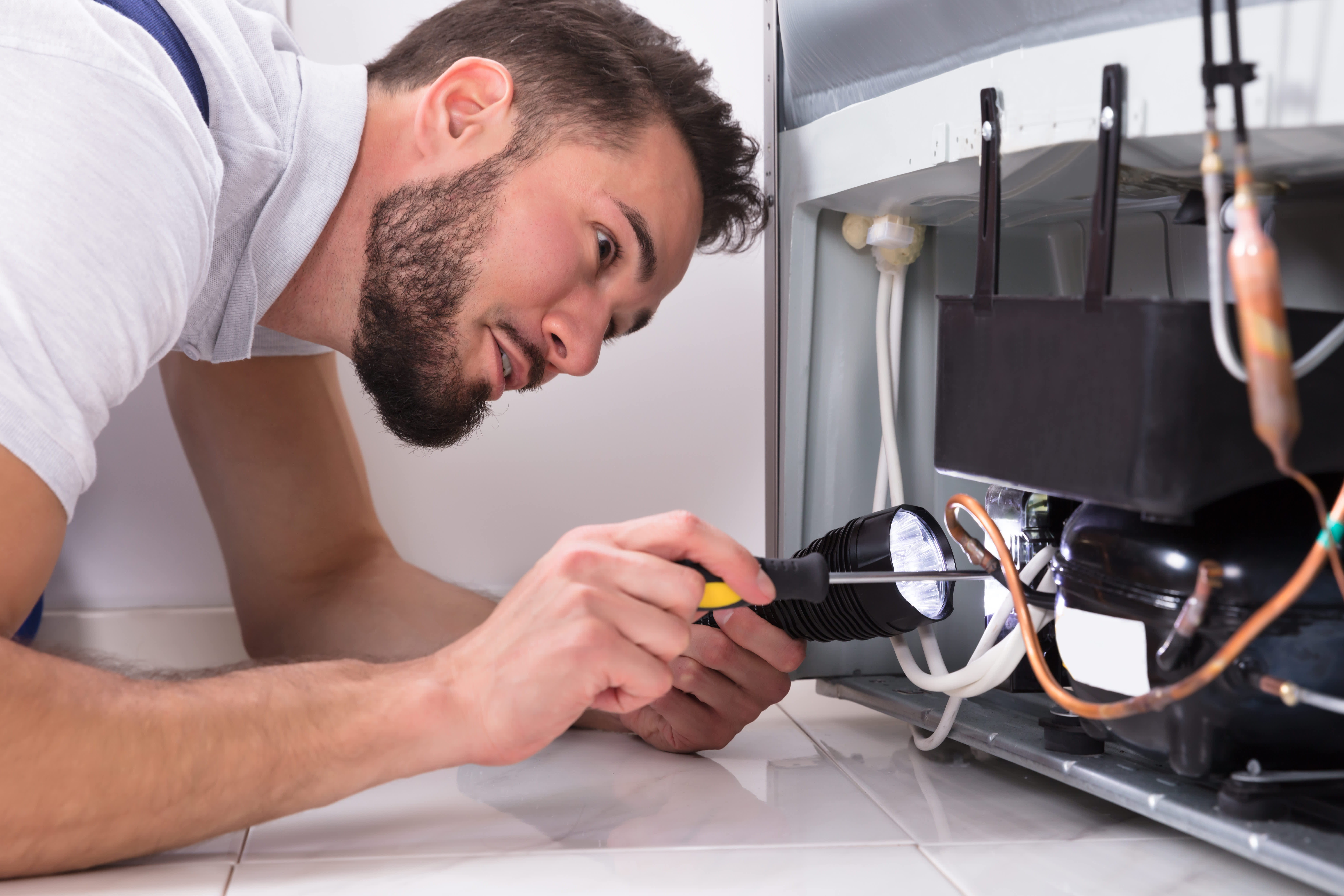 A technician fixing a freon leak of a refrigerator