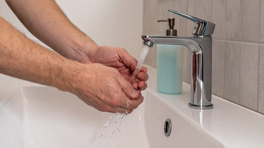 Man washing his hands in bathroom sink