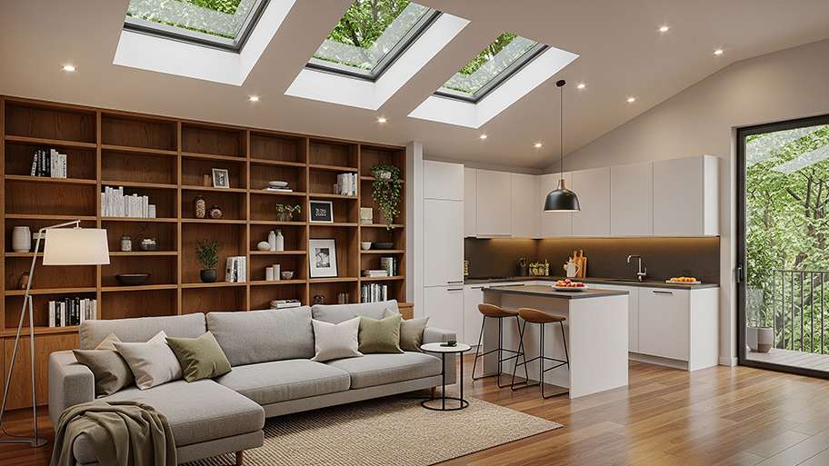 A modern open-plan room has a large bookcase, a kitchen, and a vaulted ceiling with skylights.