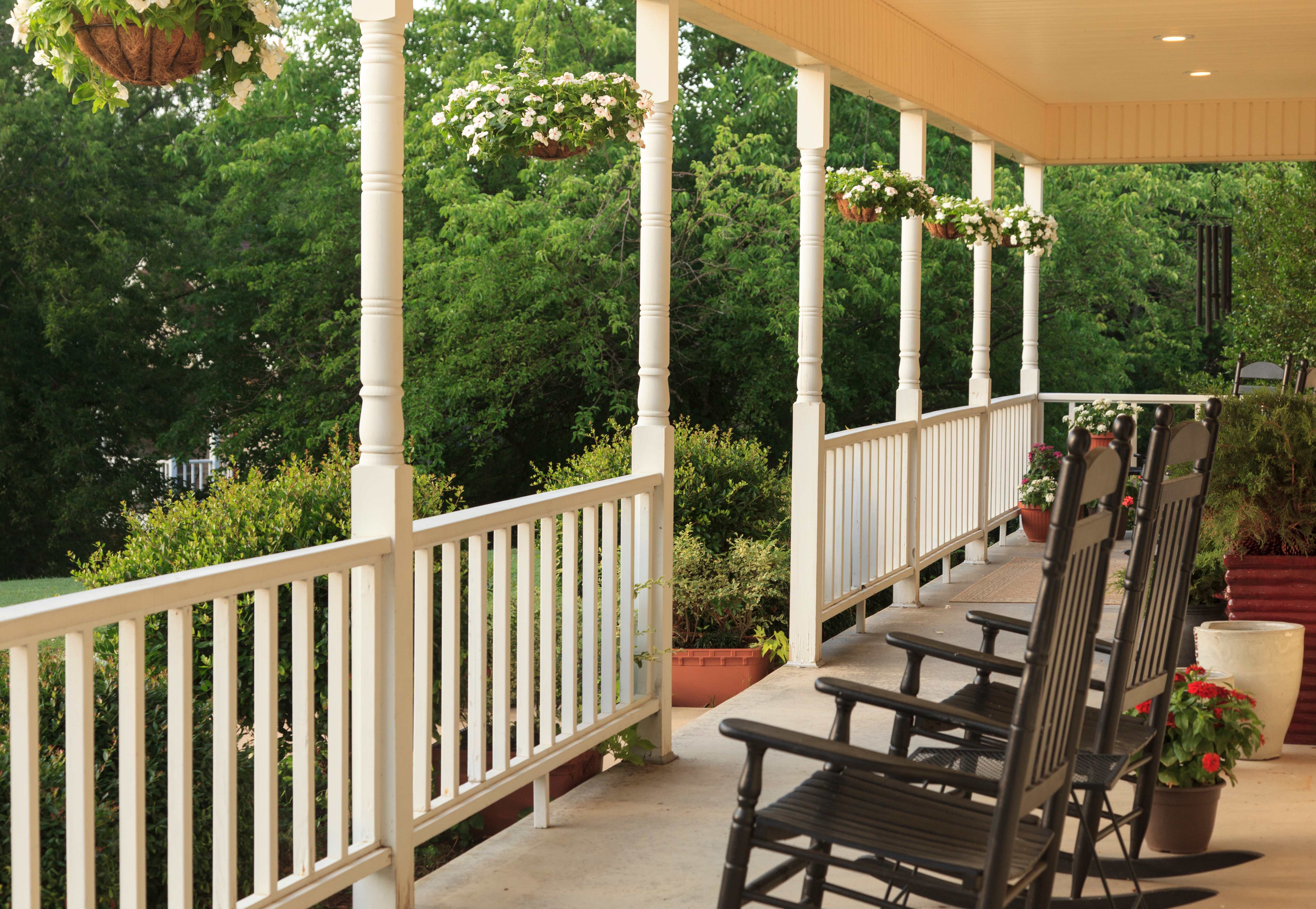 A porch with two rocking chairs and hanging pots