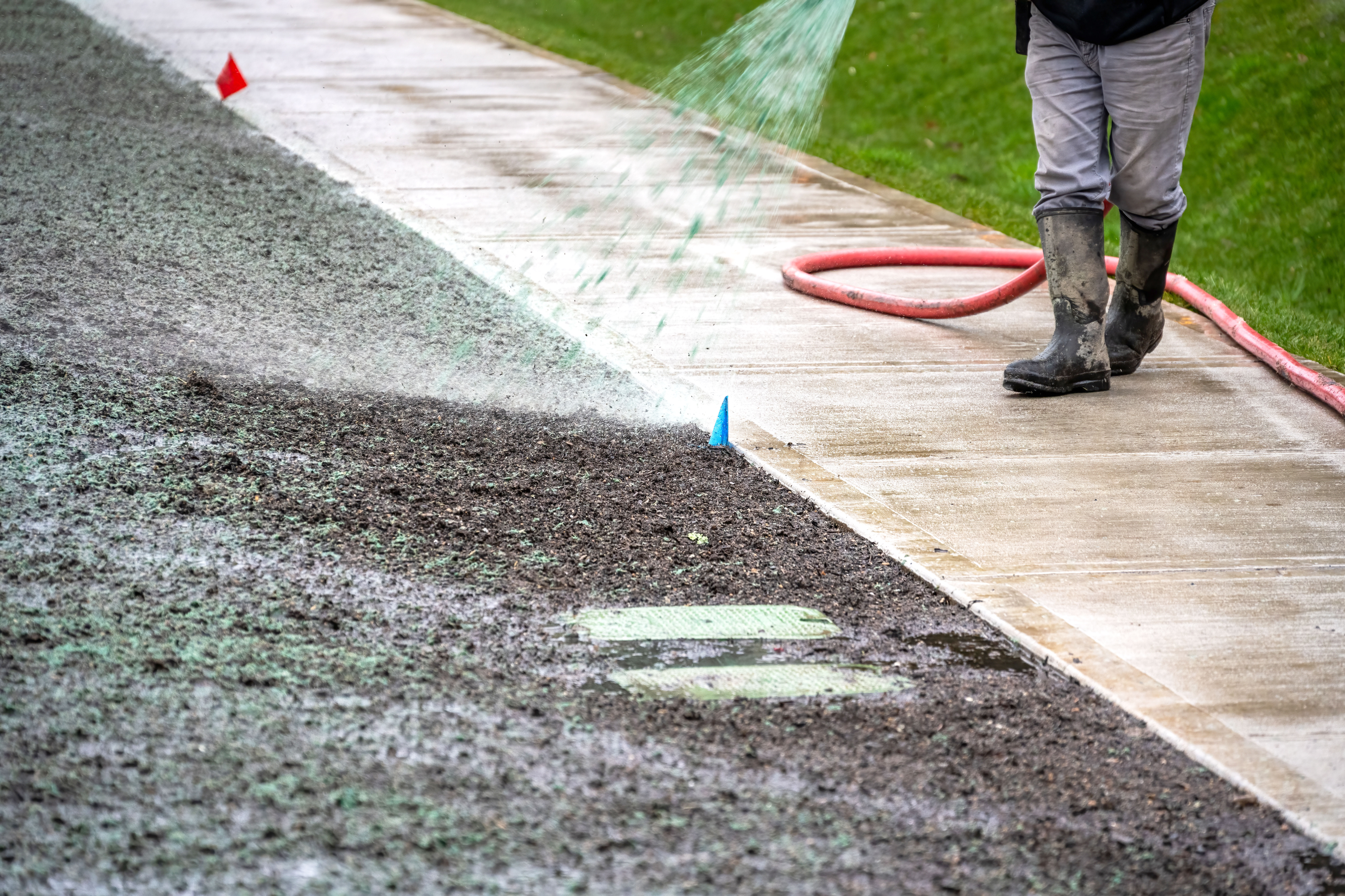 Worker spraying hydro mulch slurry directly onto soil