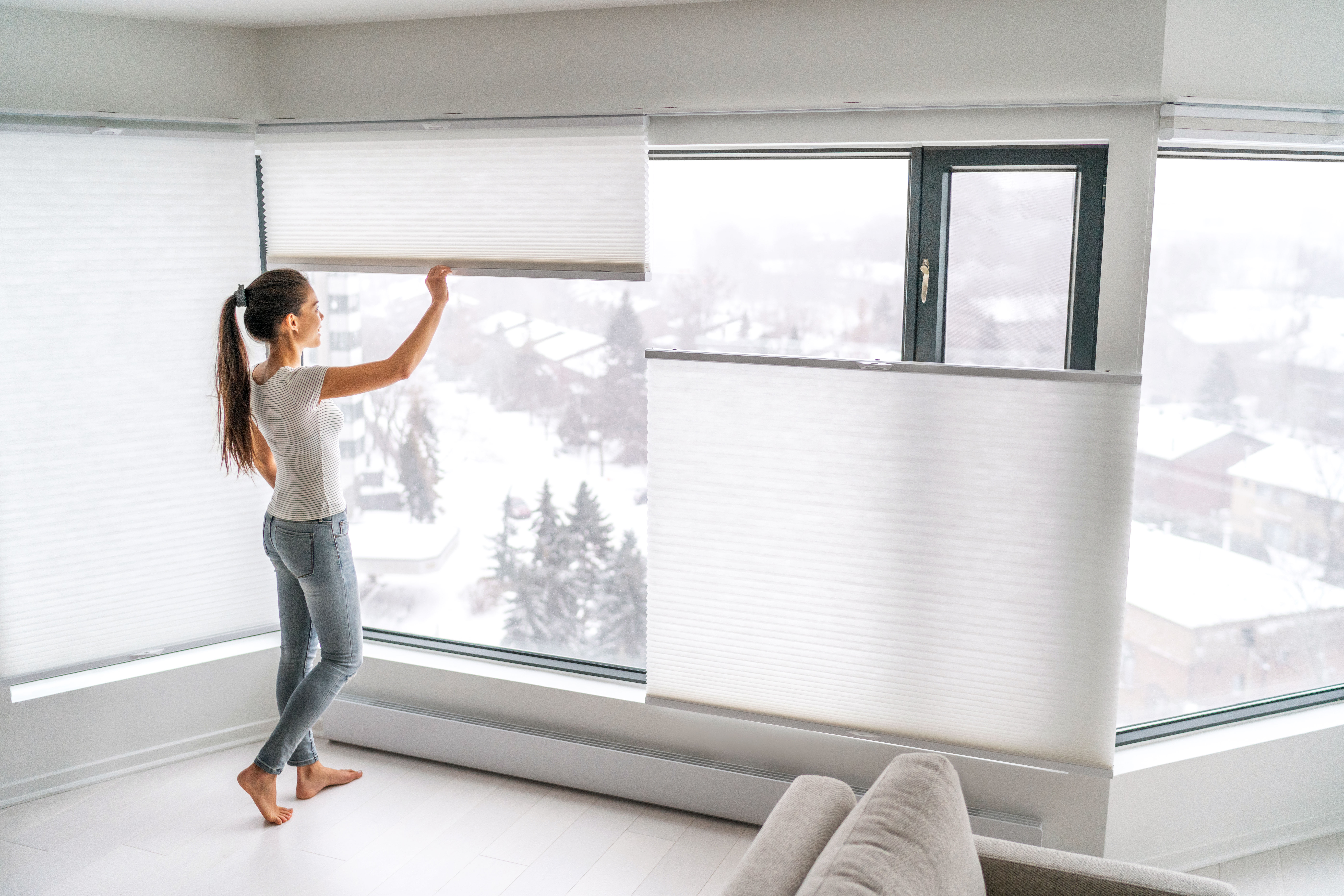 Woman closing the cellular shades in her apartment