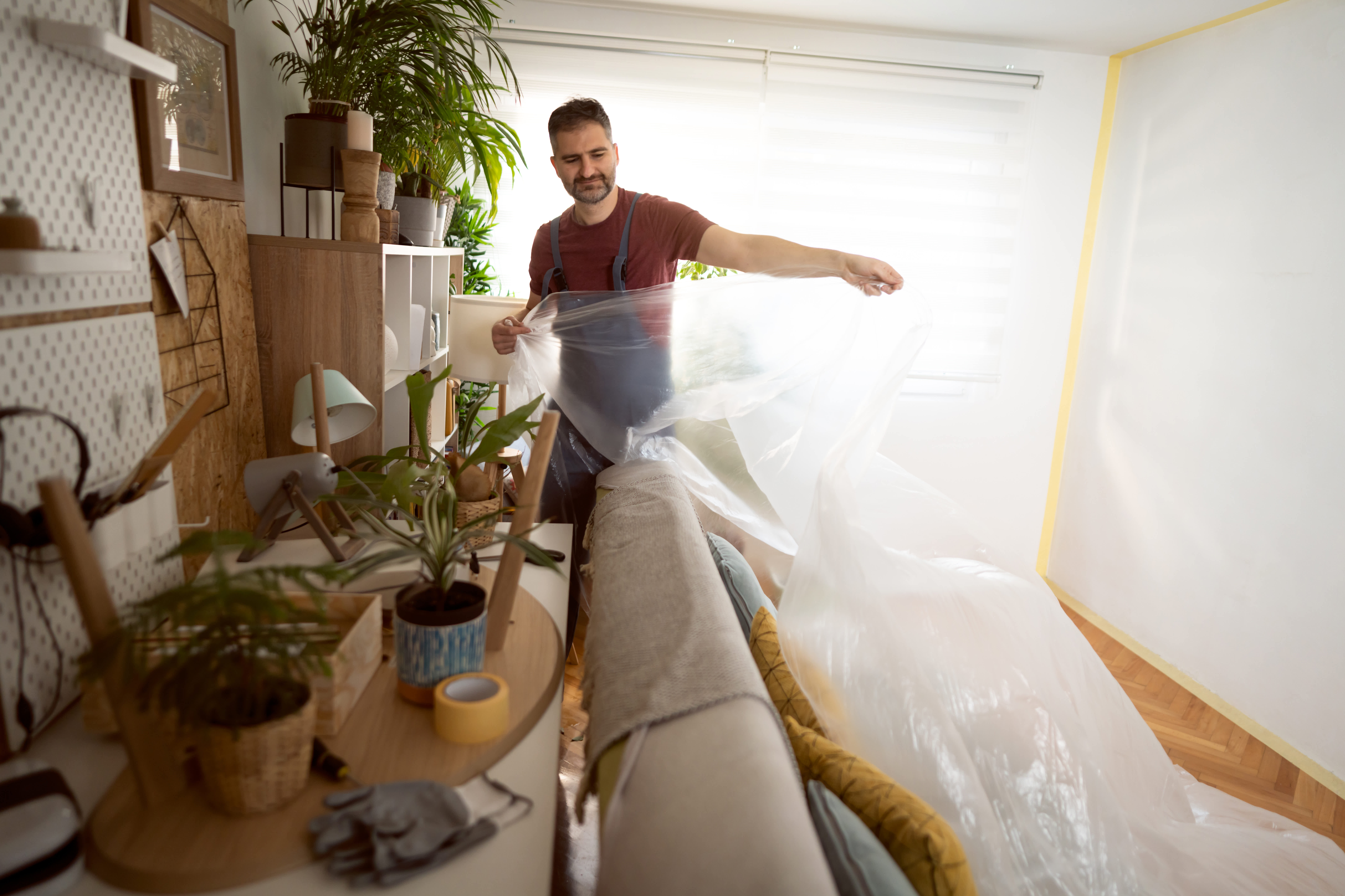 A man covering furniture before spray painting a room