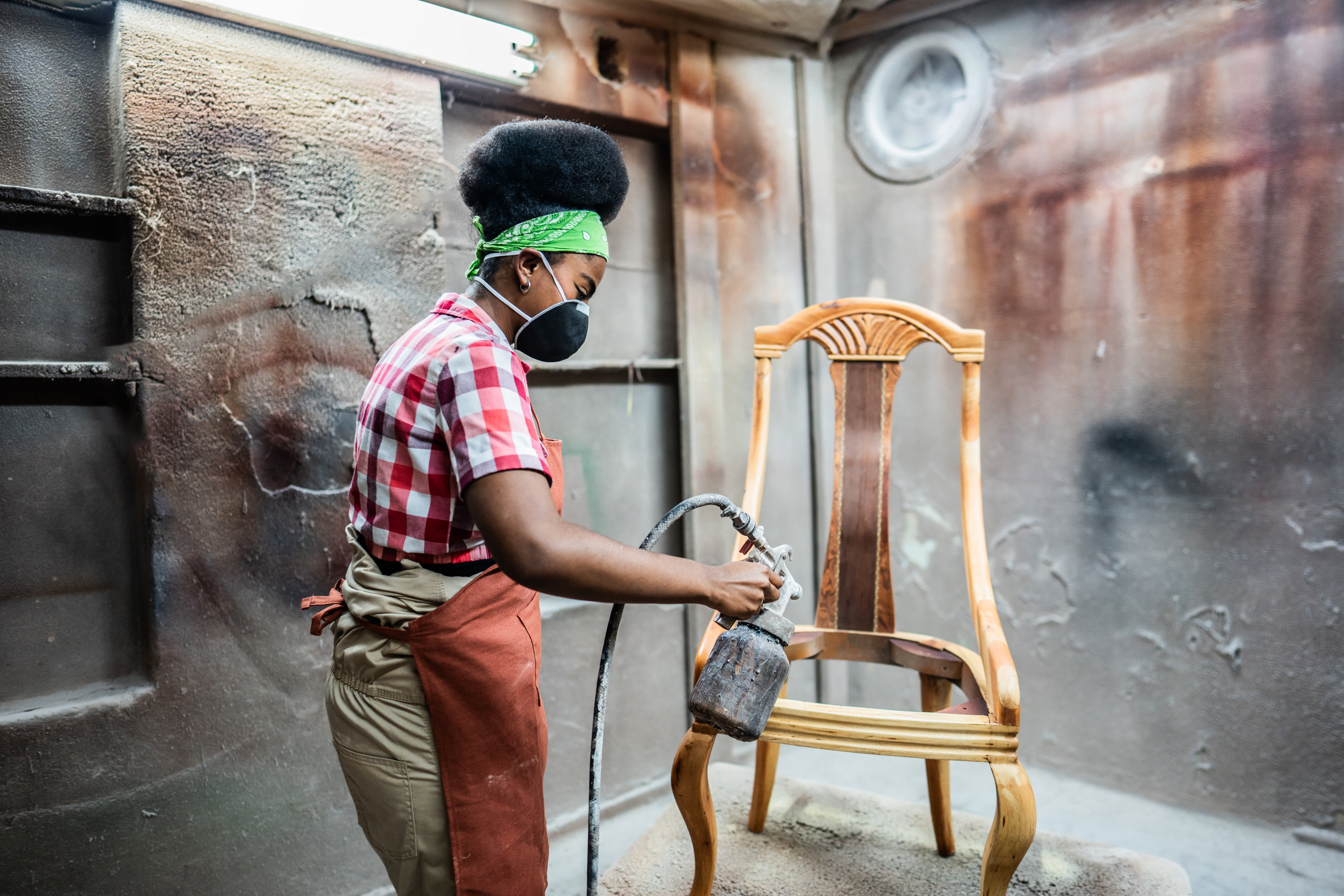 A woman spray painting a vintage chair