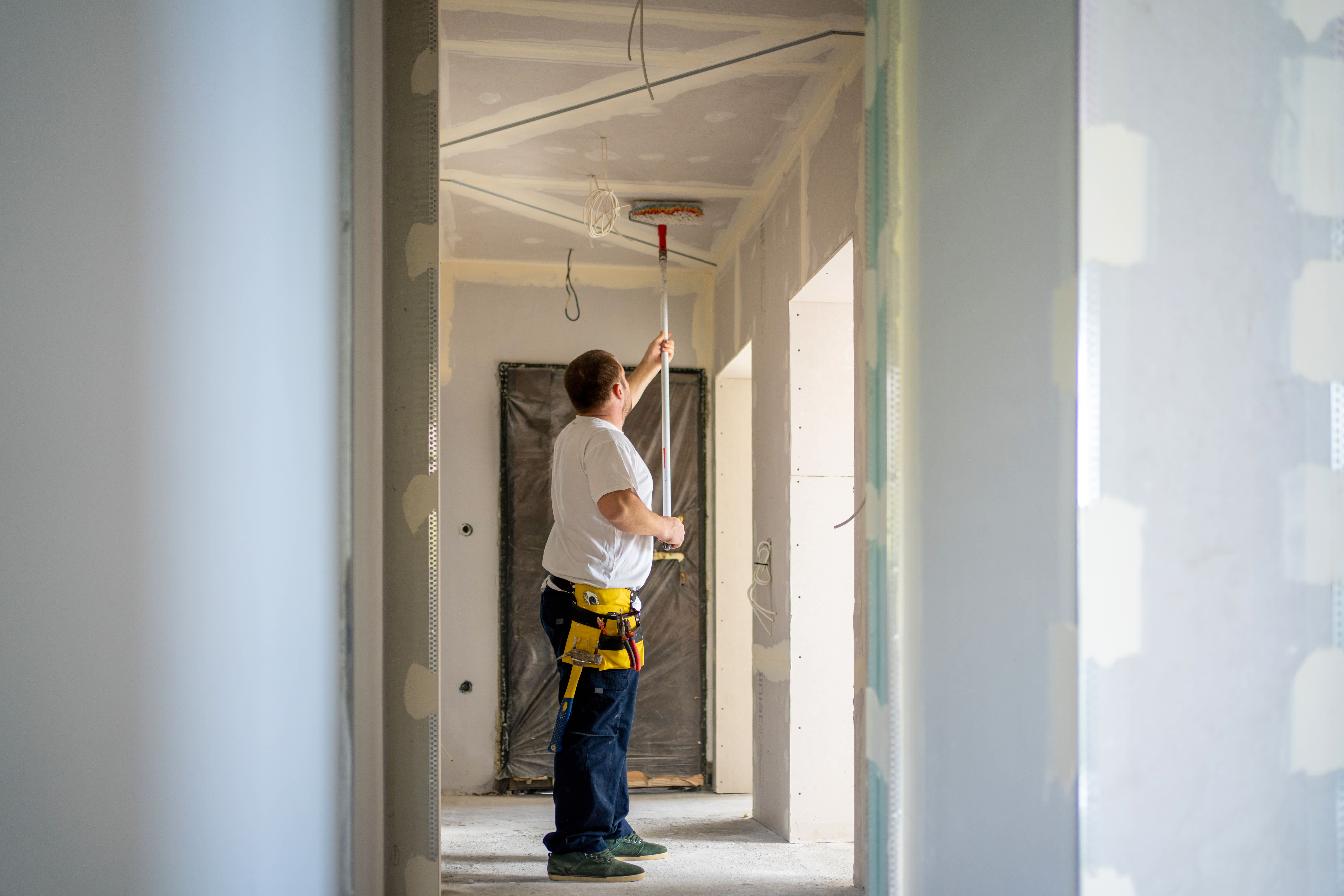 A man applying primer on the ceiling with a roller