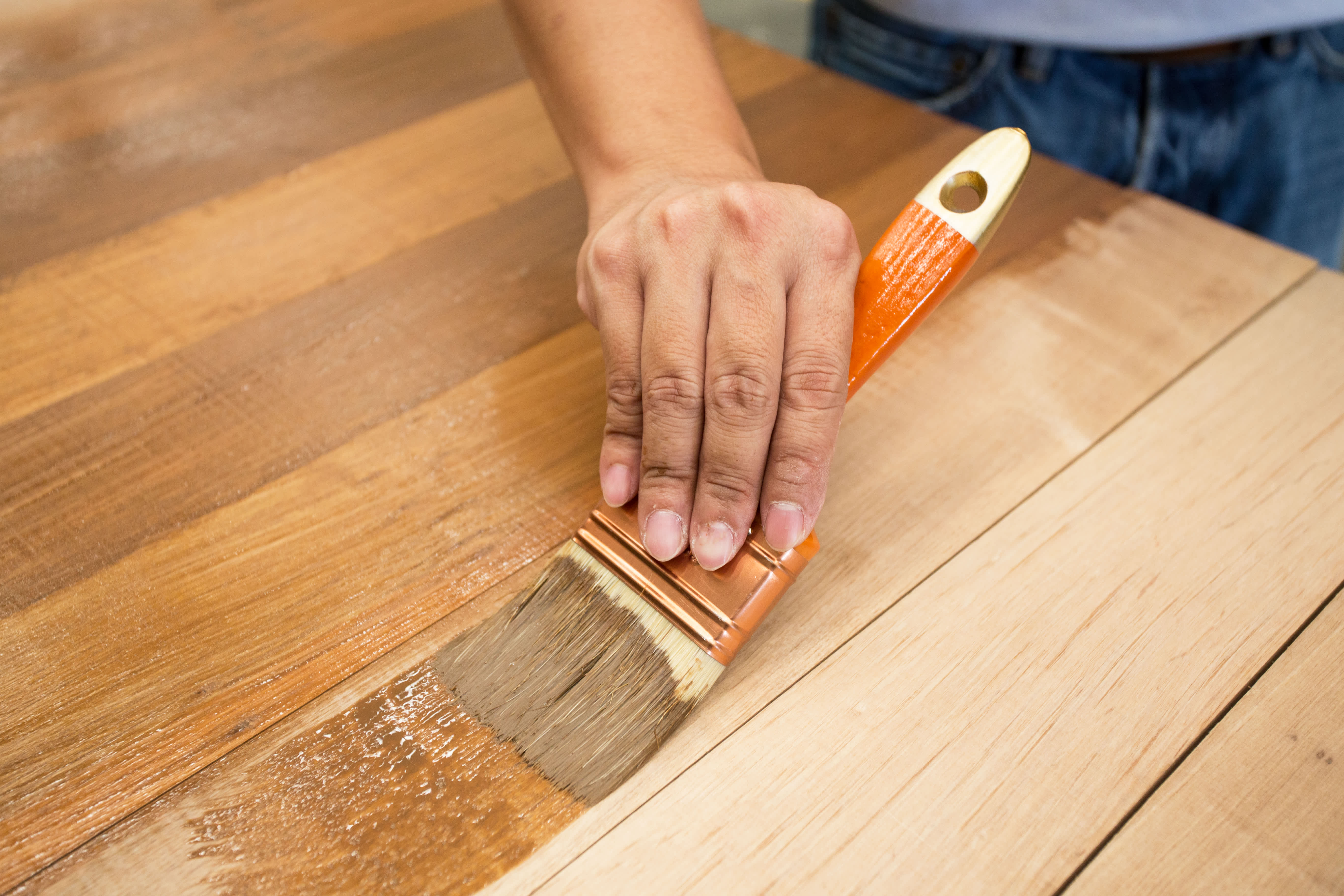 Man applying protective varnish on a wooden furniture