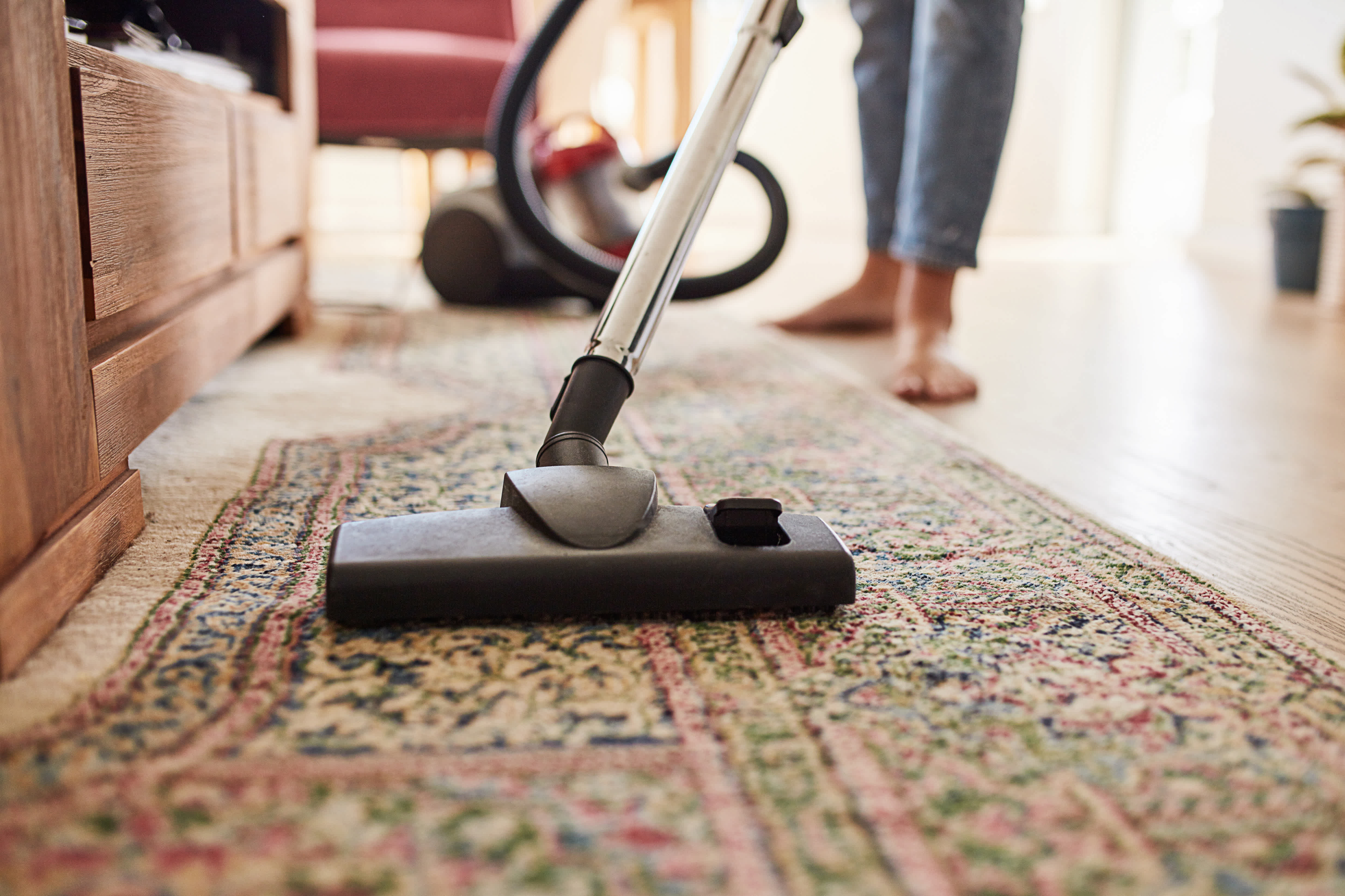A person vacuuming a rug