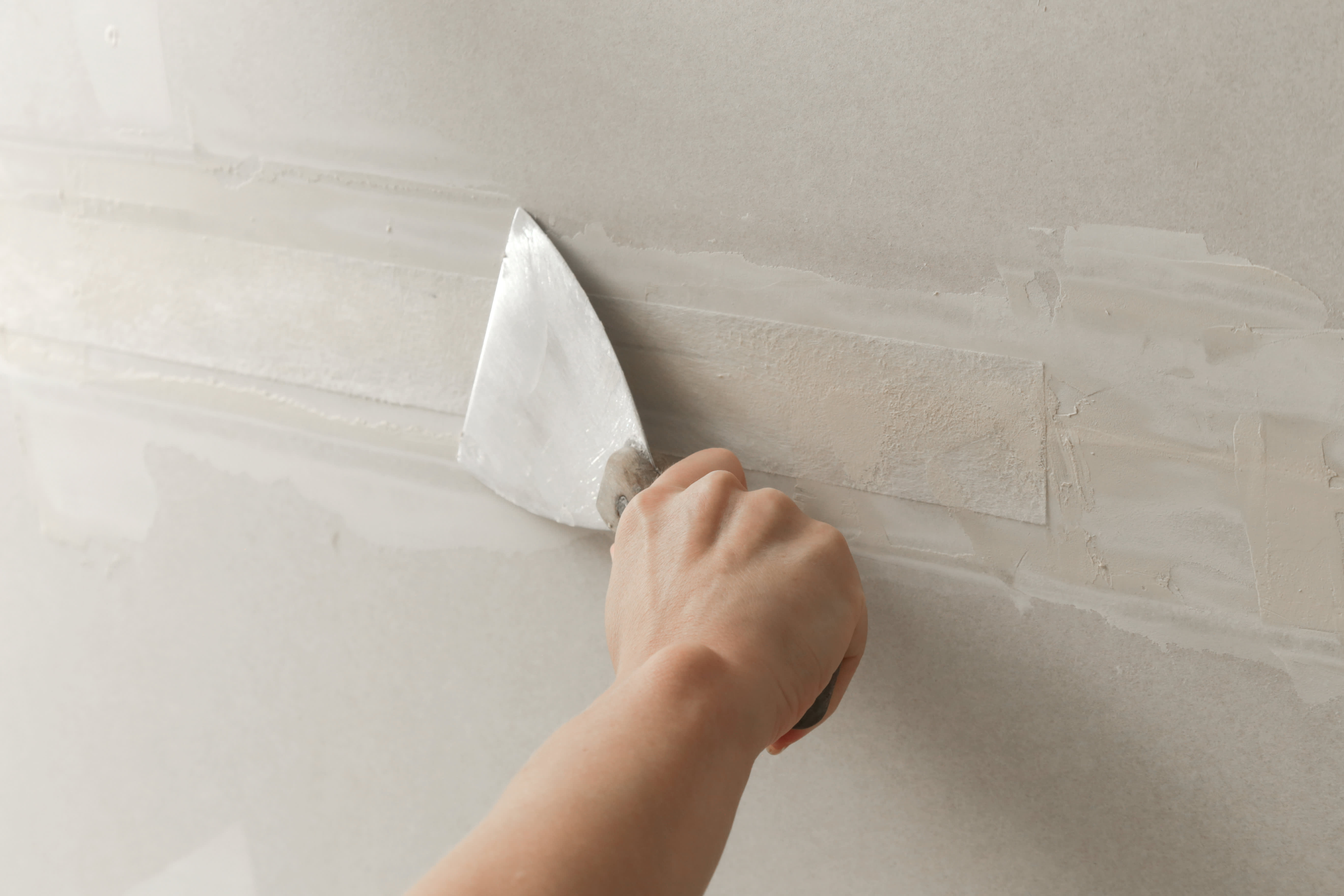 Close-up of a person taping and mudding a drywall