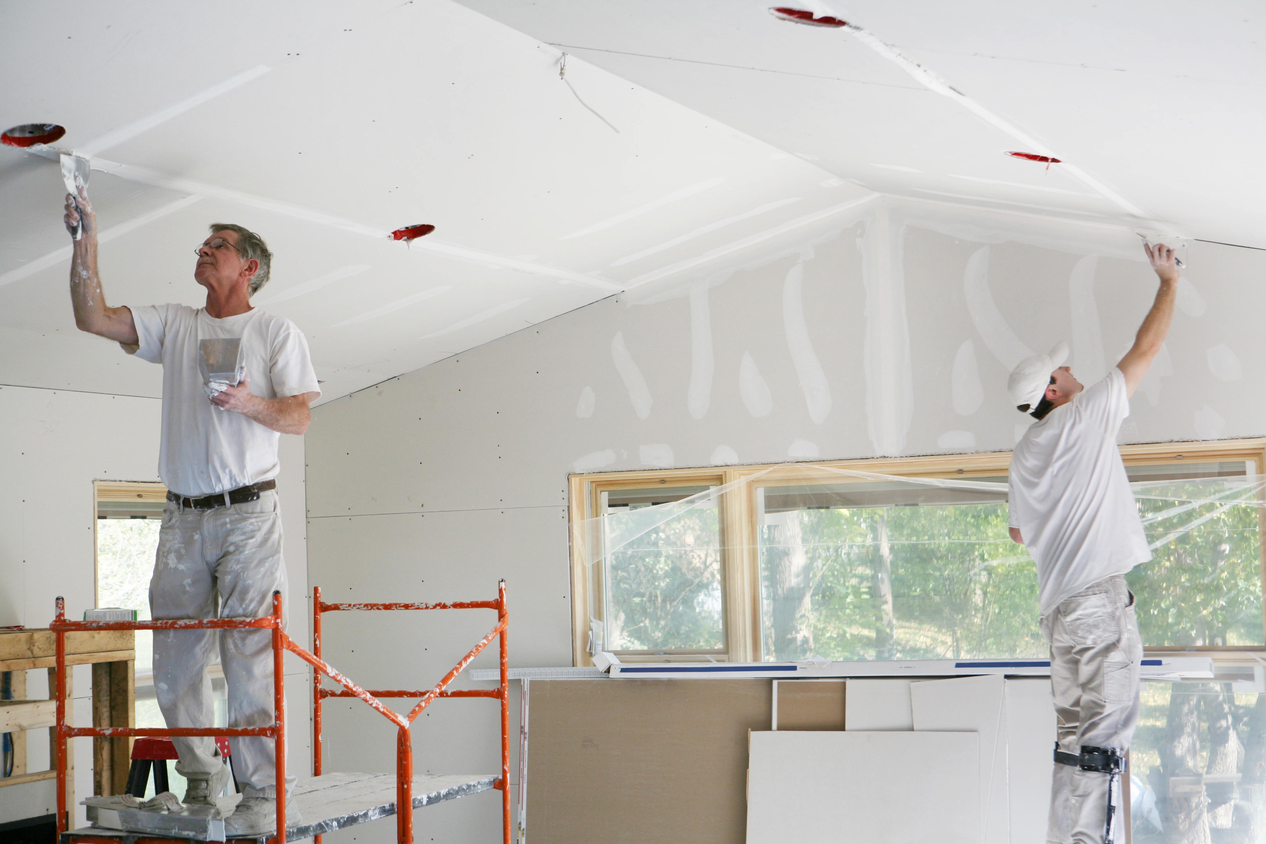 Two professionals mudding a drywall