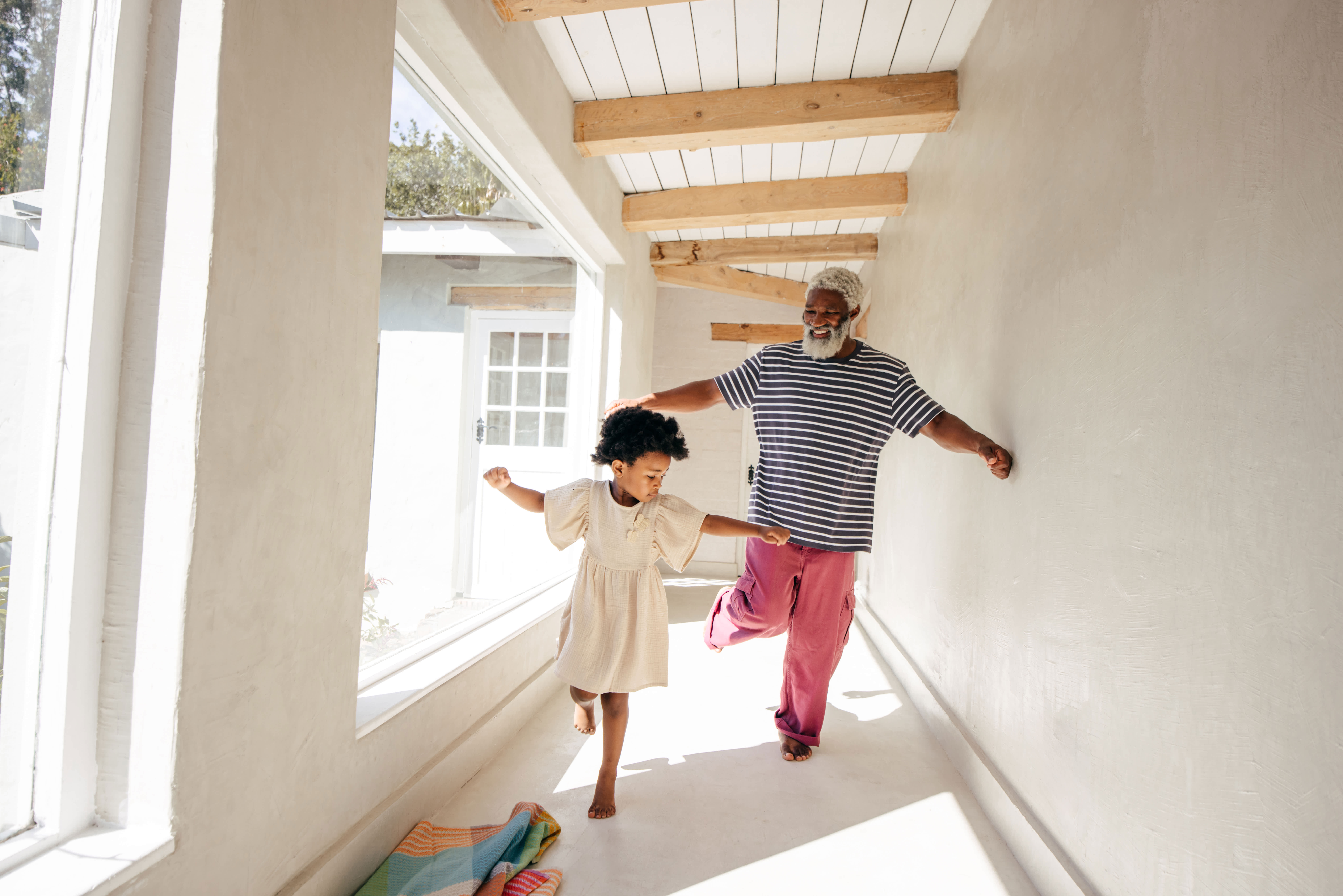 Grandfather and granddaughter dancing and playing in the hallway