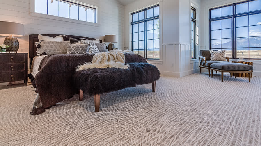Modern farmhouse bedroom with large windows, cozy carpet, and mountain views