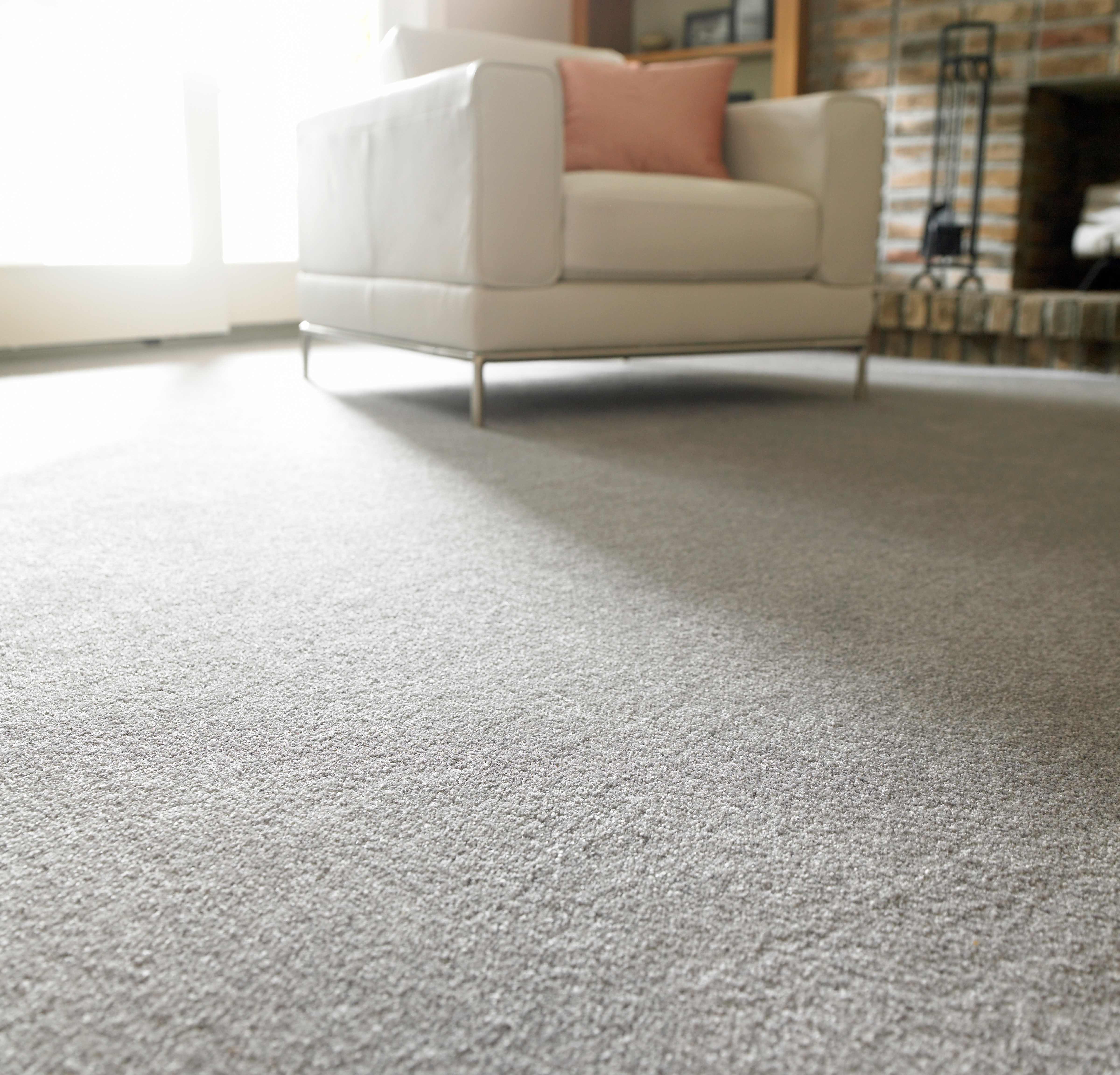 Close-up of light gray carpet in a modern living room with a white chair