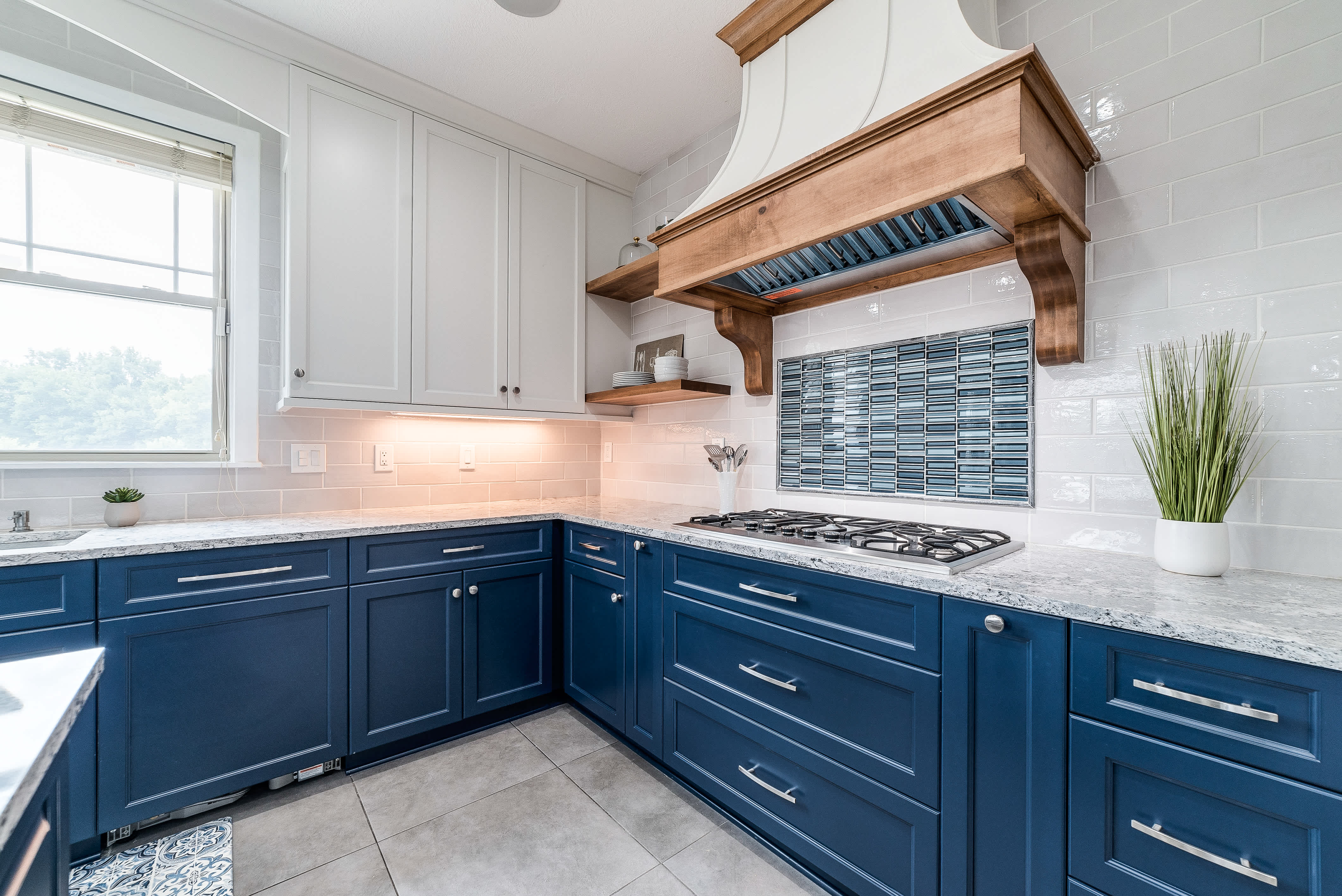 Modern kitchen with blue lower cabinets, white upper cabinets, and a decorative tile backsplash