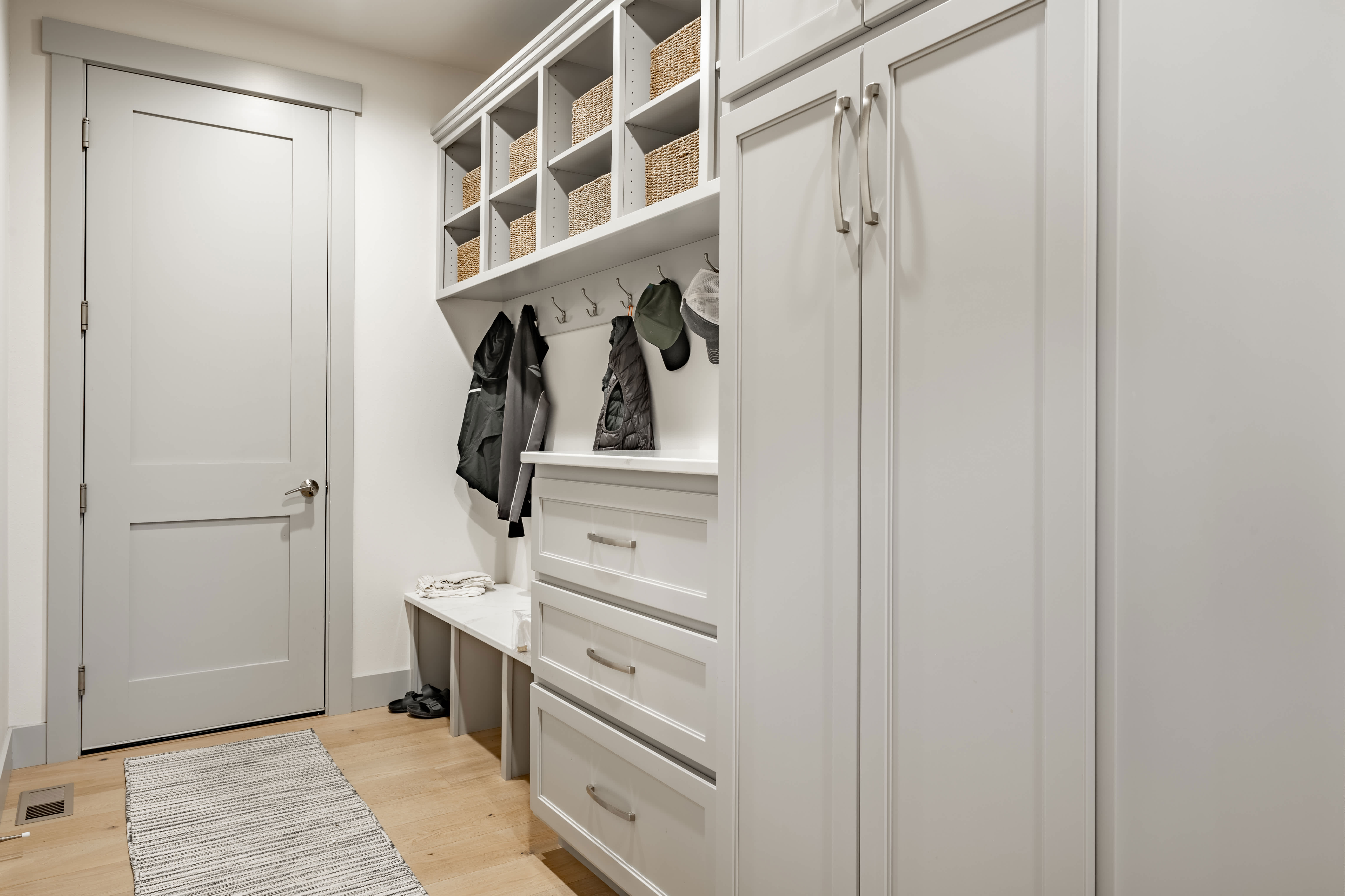 Modern mudroom with white built-in cabinets, cubbies, and coat hooks