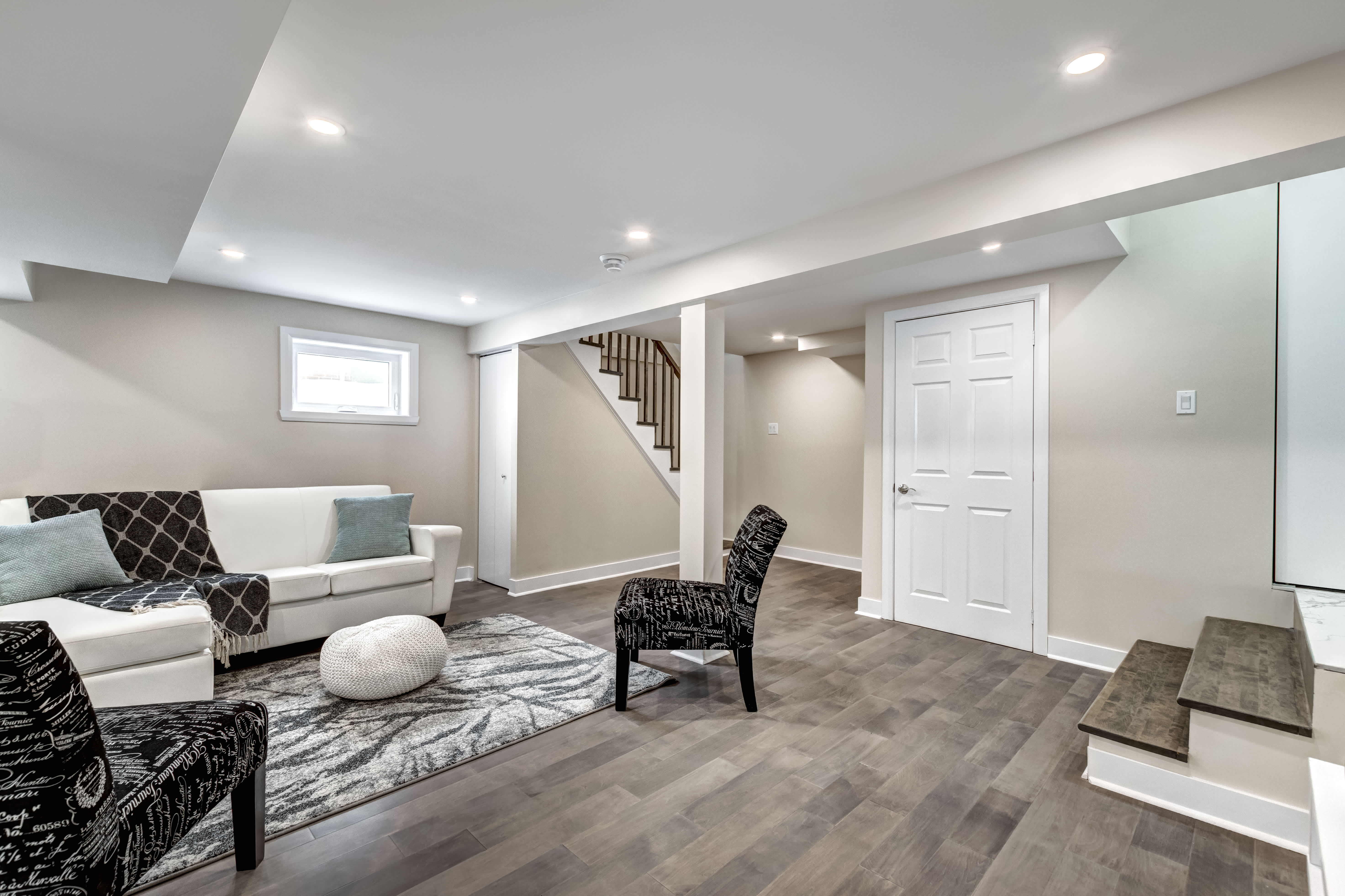 Finished basement with neutral walls, wood-look flooring, and cozy seating area