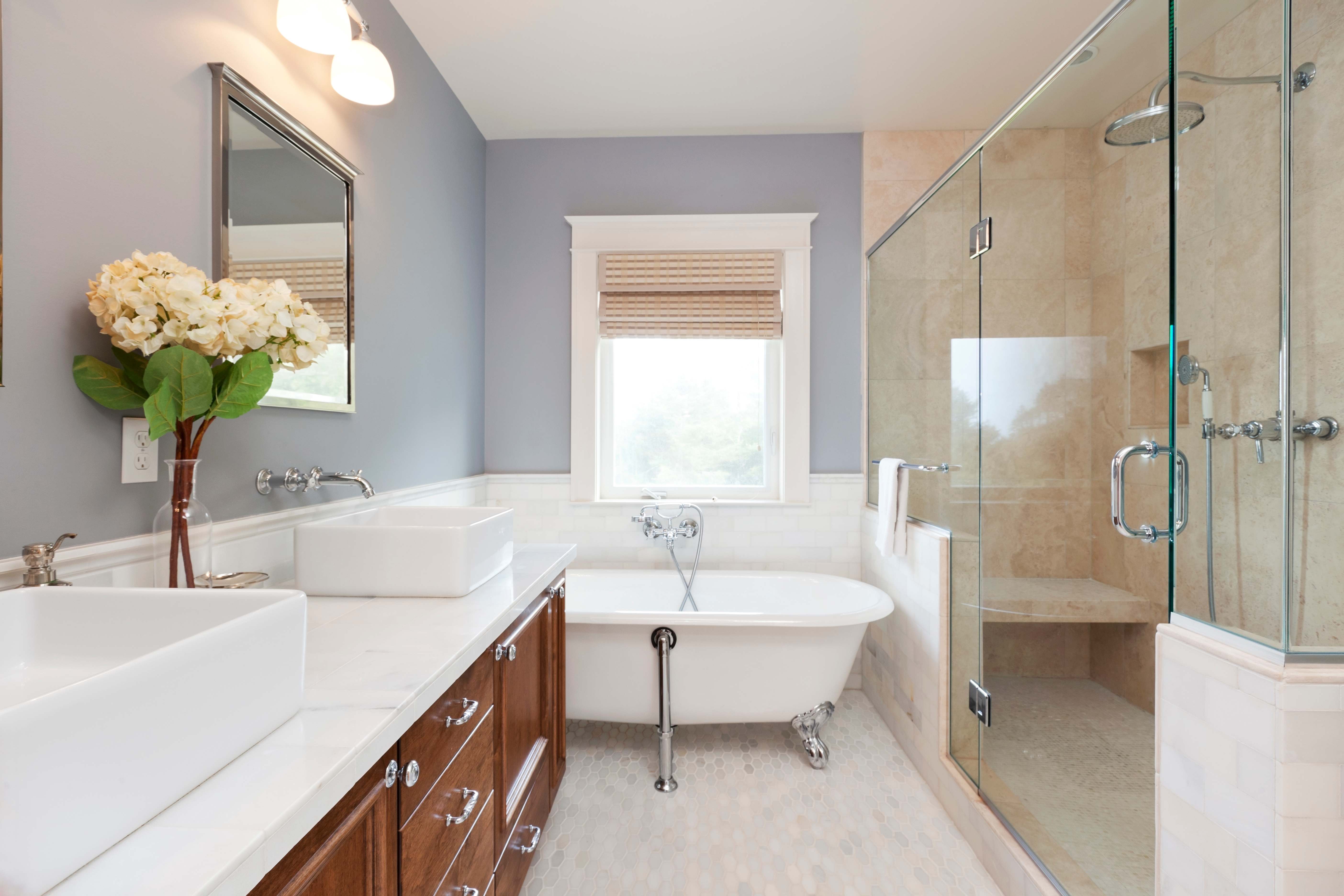 Modern bathroom with white freestanding tub, double sinks, large mirror, and soft natural light through windows