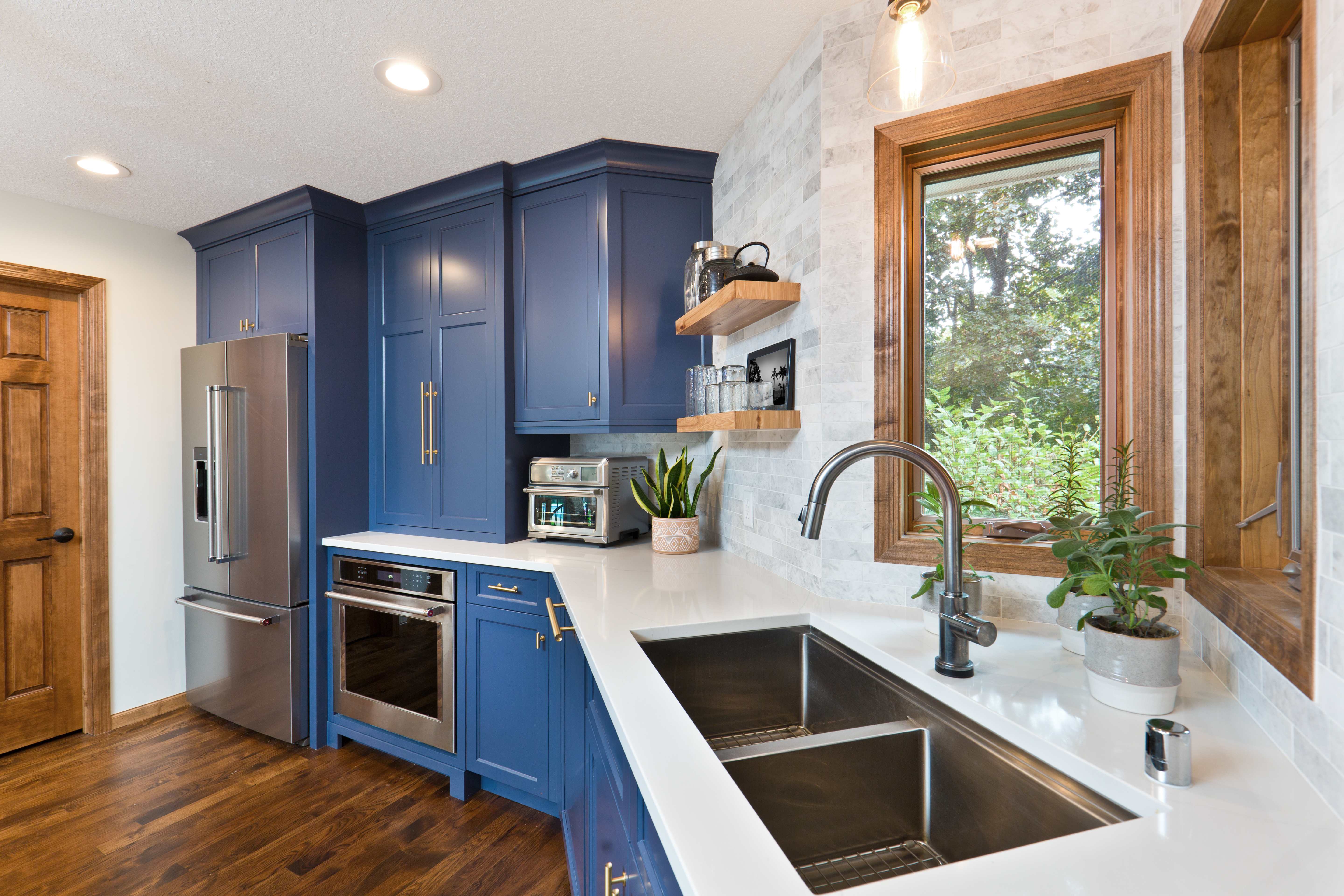 Contemporary remodeled kitchen with white cabinets, marble island, pendant lights, and stainless steel appliances