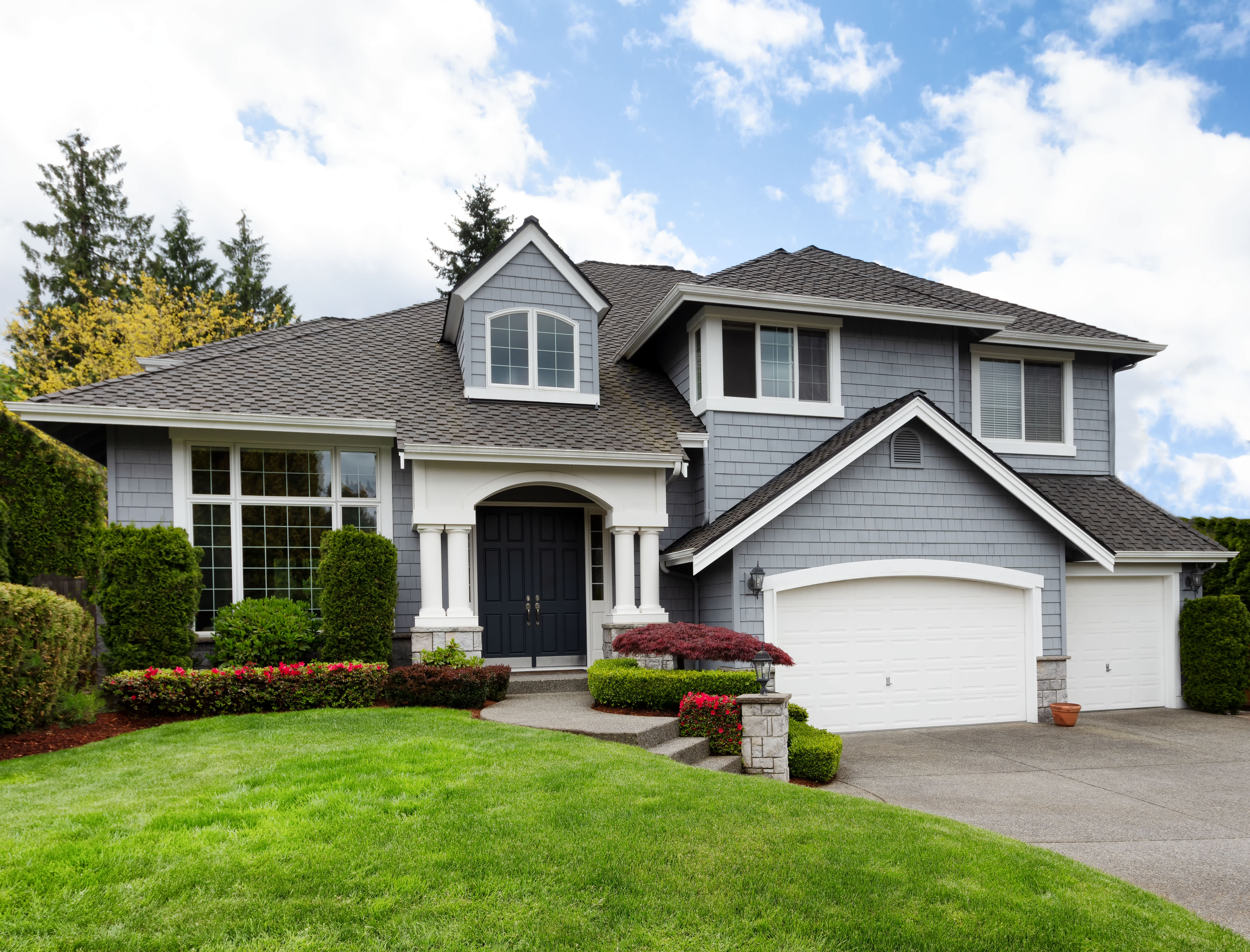Charming home with lush green lawn, blooming spring flowers, and a neat front yard surrounded by trees and shrubs