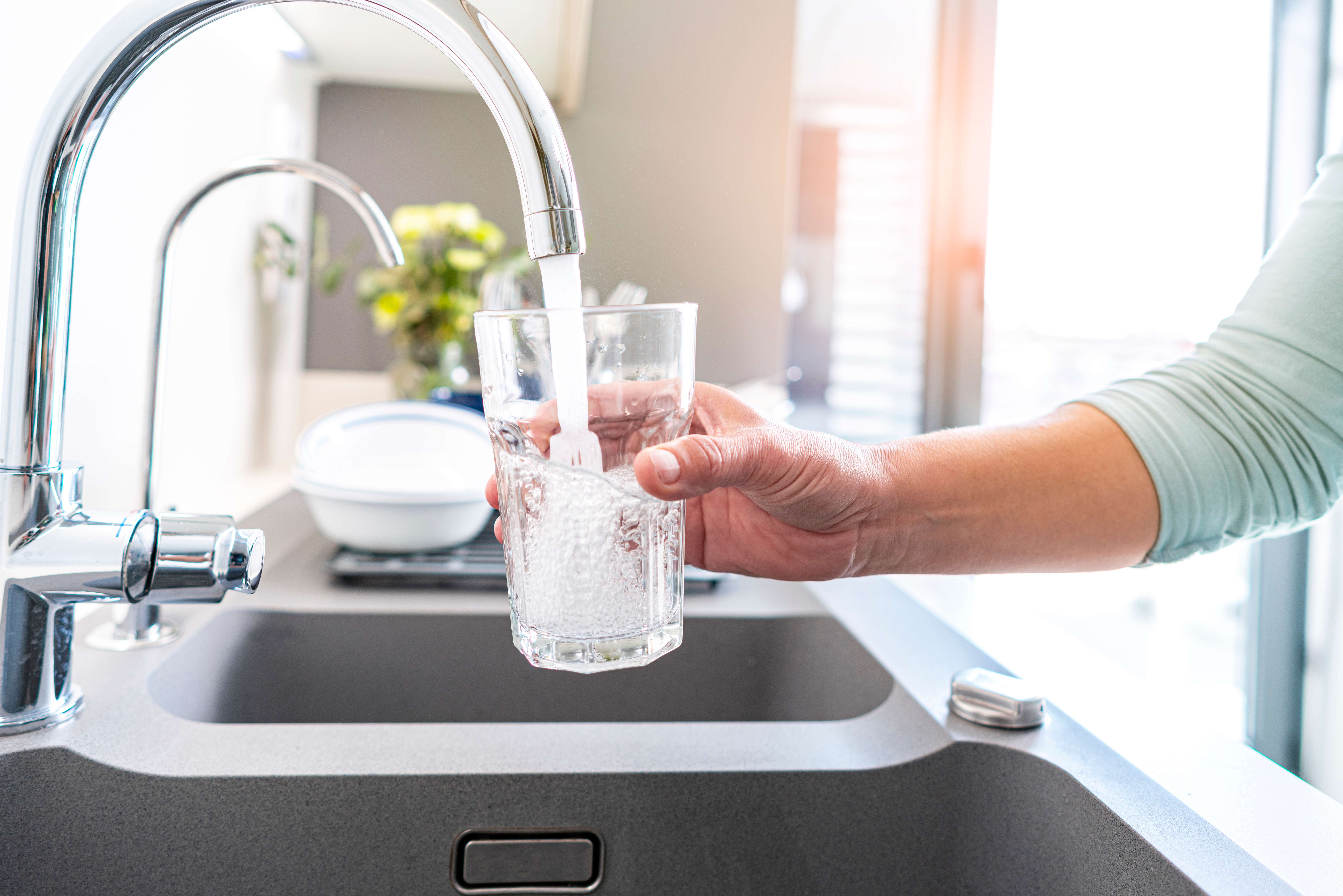 Close-up of clear water pouring from kitchen faucet into a glass, symbolizing freshness and clean hydration