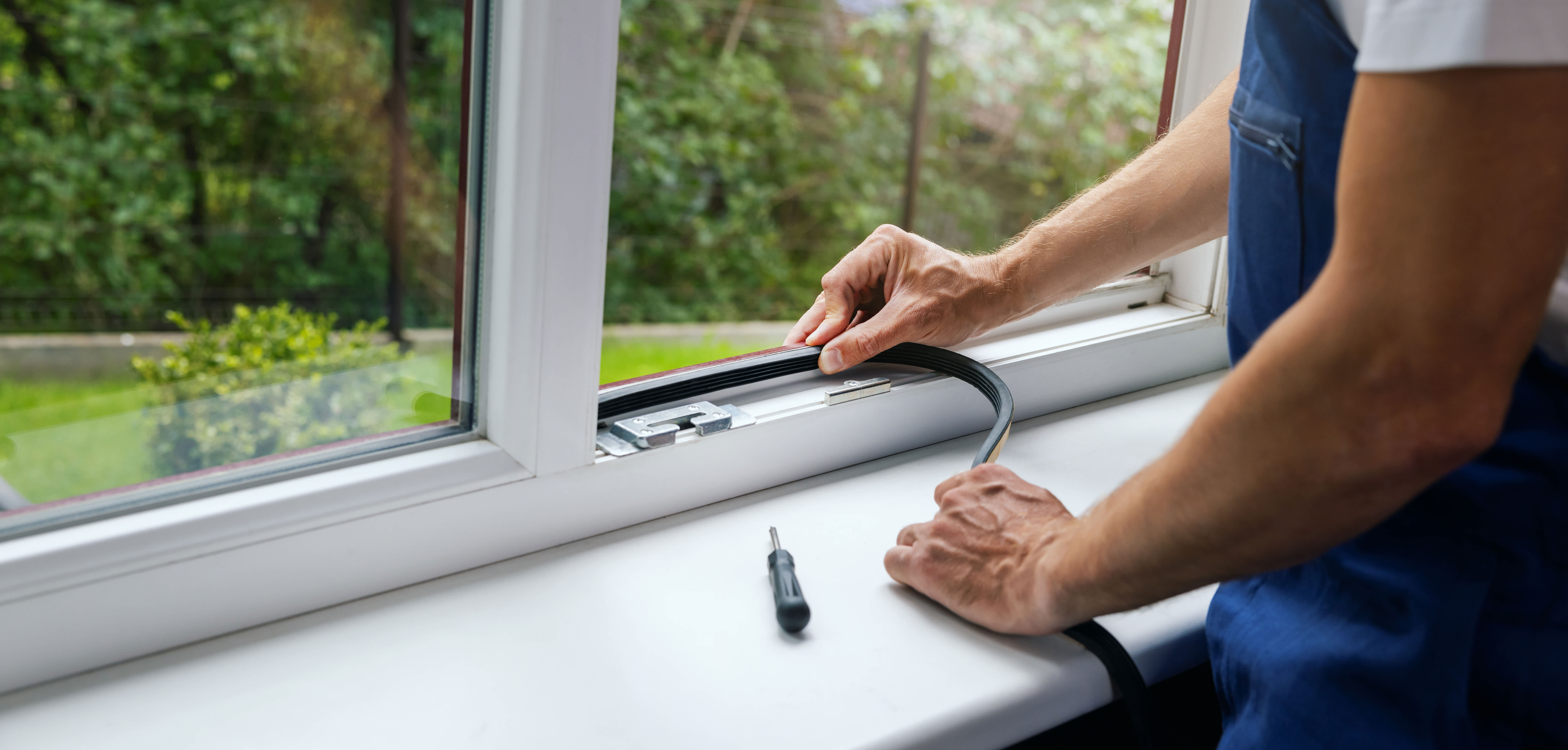 Worker installing sealing tape on a plastic window frame, ensuring proper insulation and energy efficiency at home