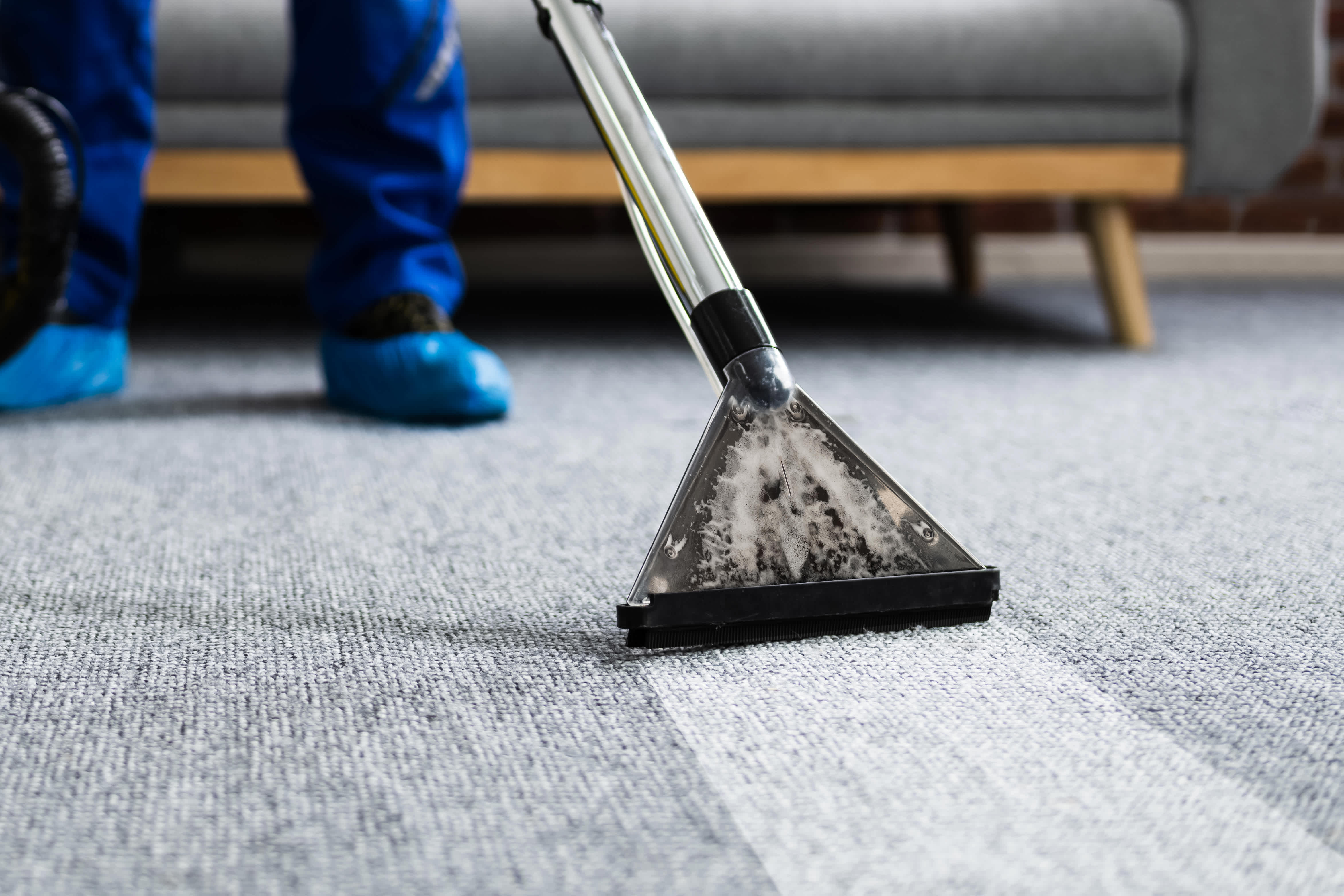 Professional carpet cleaning in progress with a steam cleaning machine, showing clear contrast between cleaned and uncleaned areas