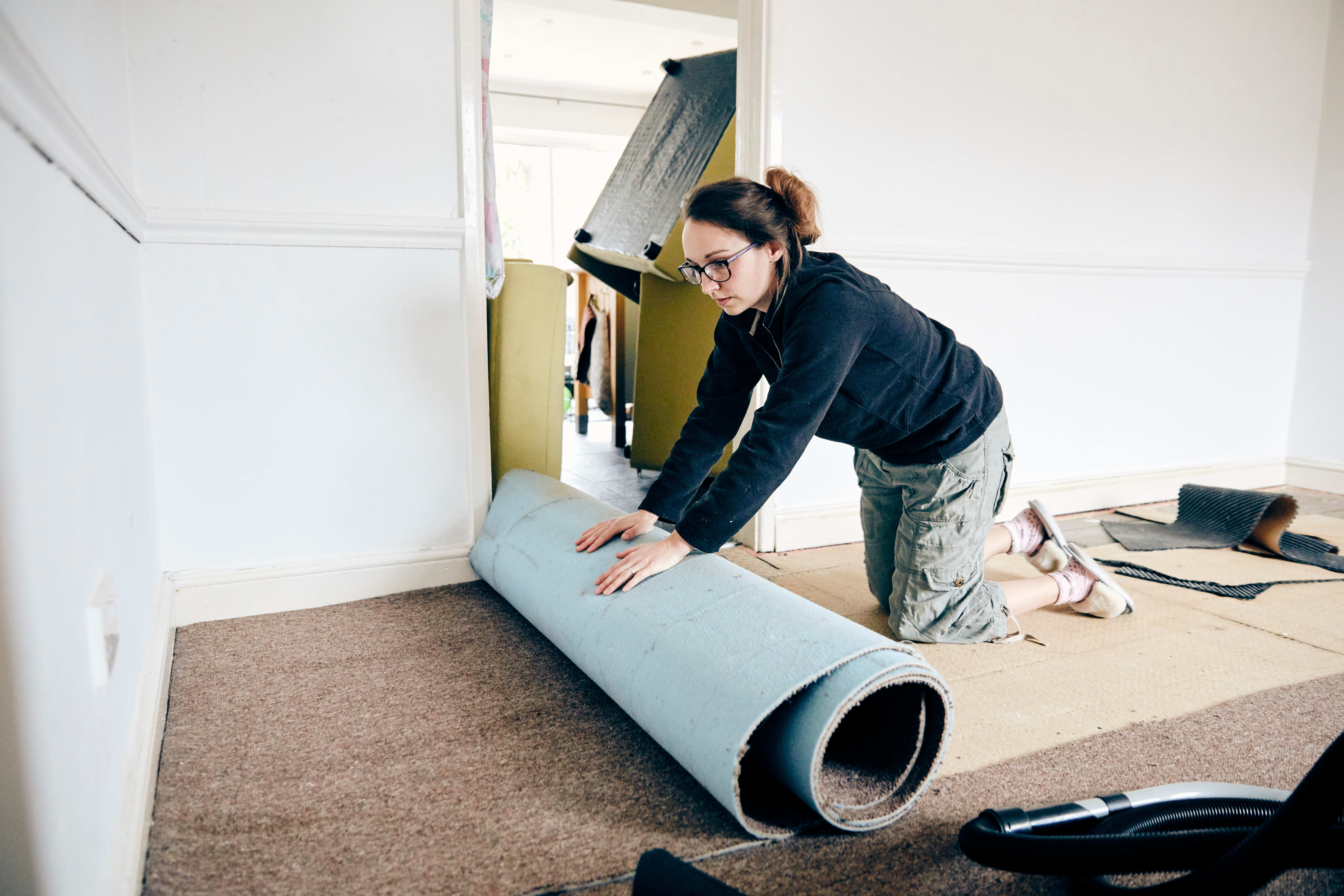 woman rolling up old carpet