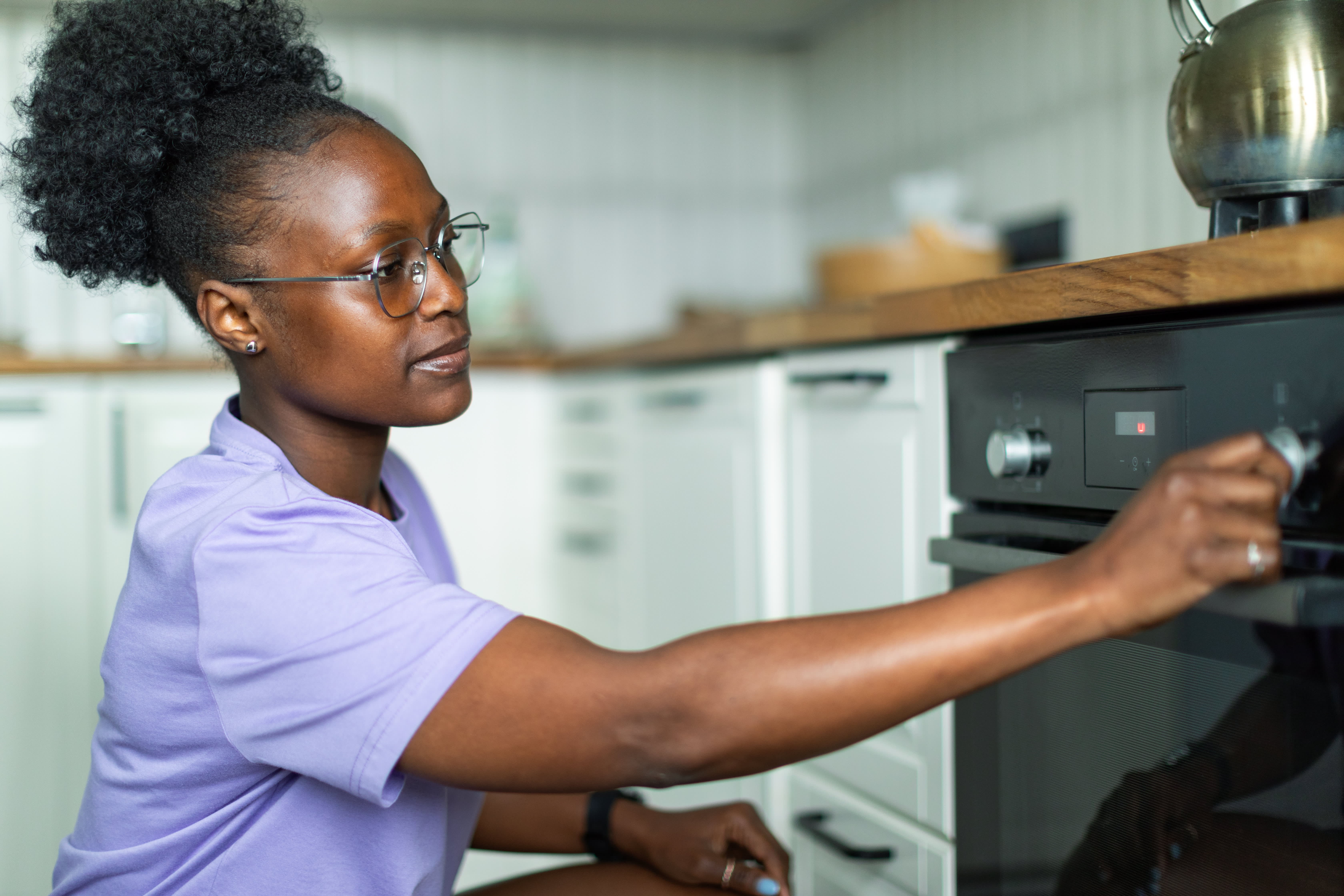 Woman switching on electric oven