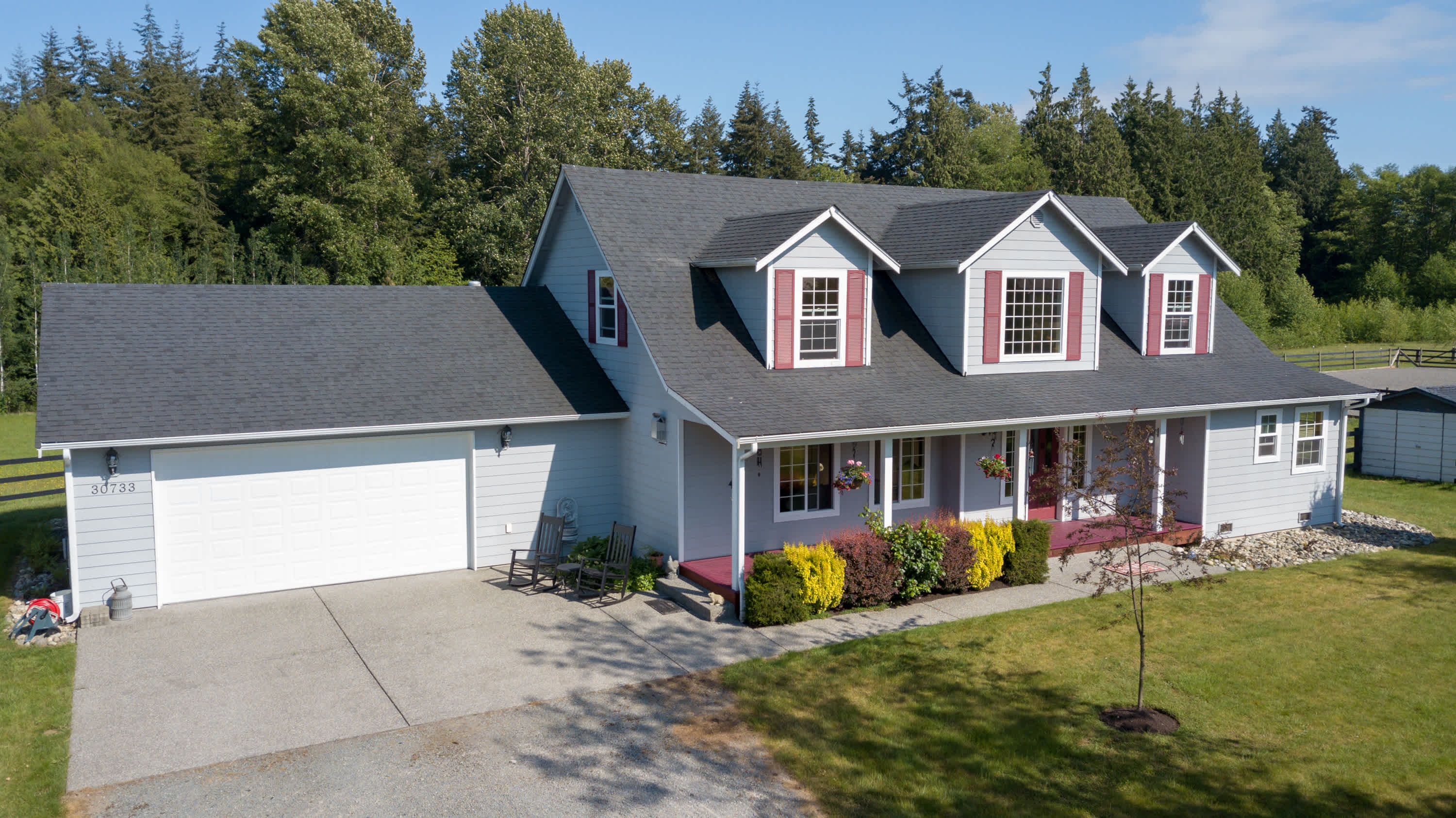 Rural house with asphalt shingle roof and red window shutters
