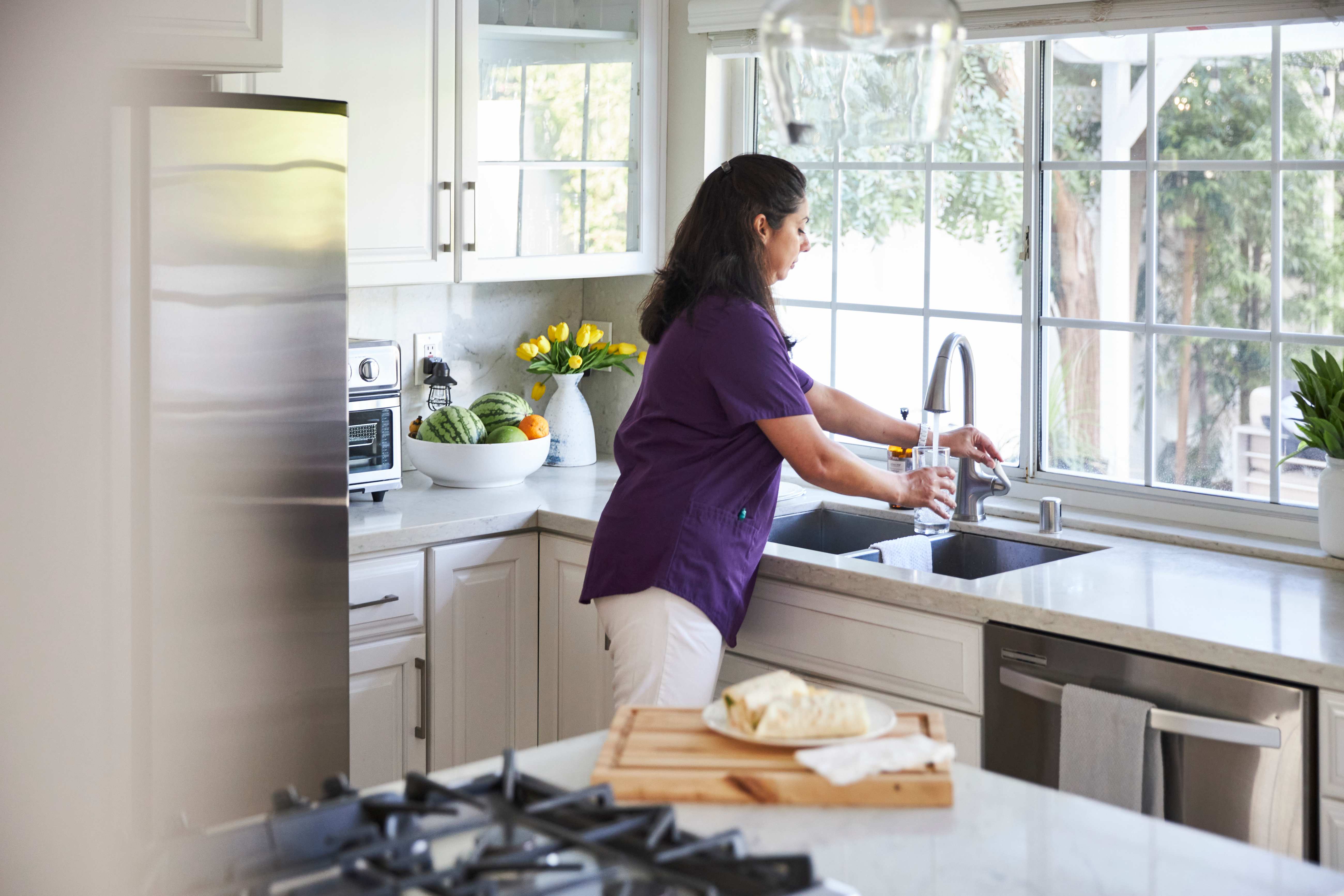 Caregiver in the kitchen filling a glass with tap water