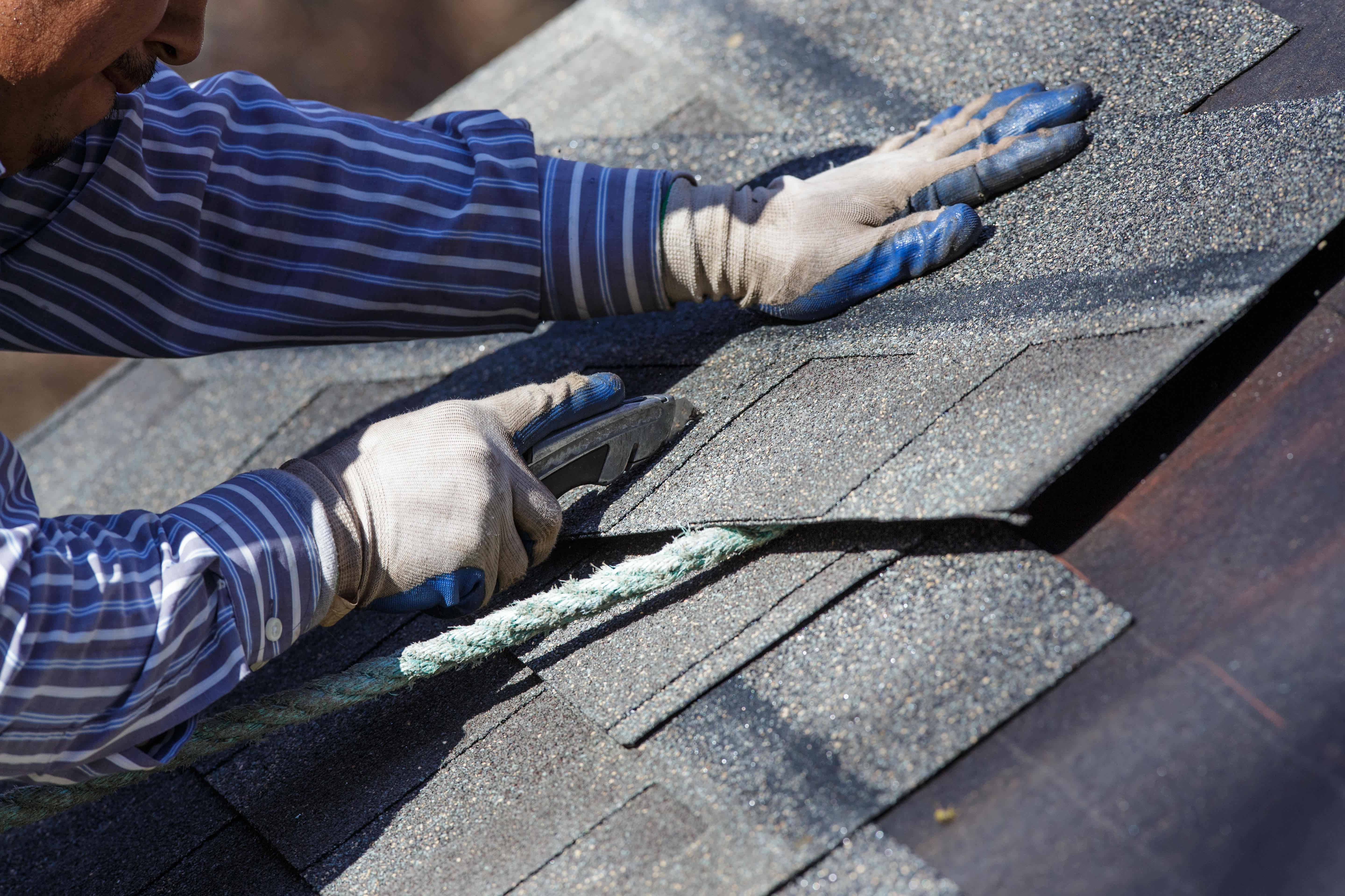 Worker cutting shingle to fit
