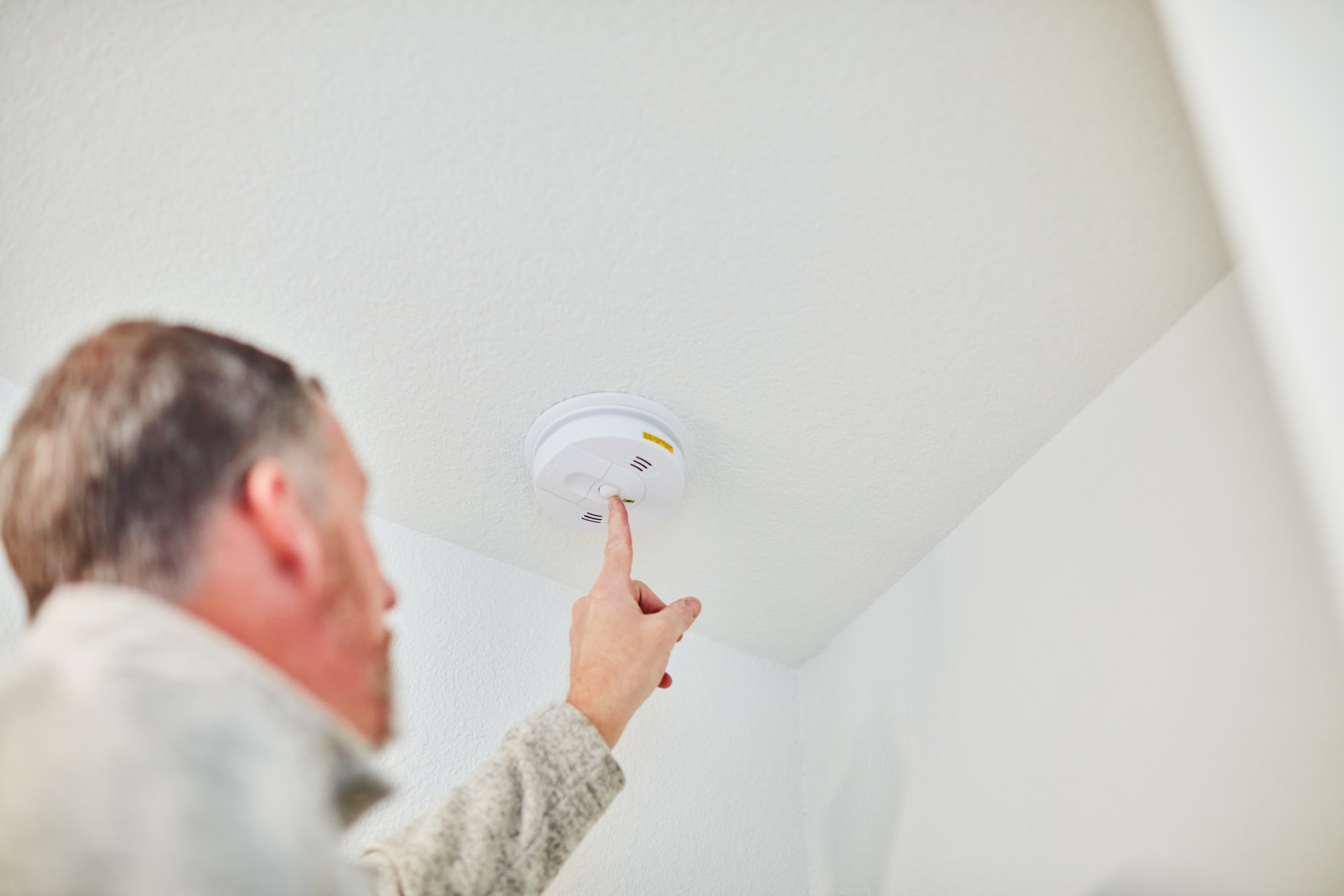 Man checking fire alarm in home