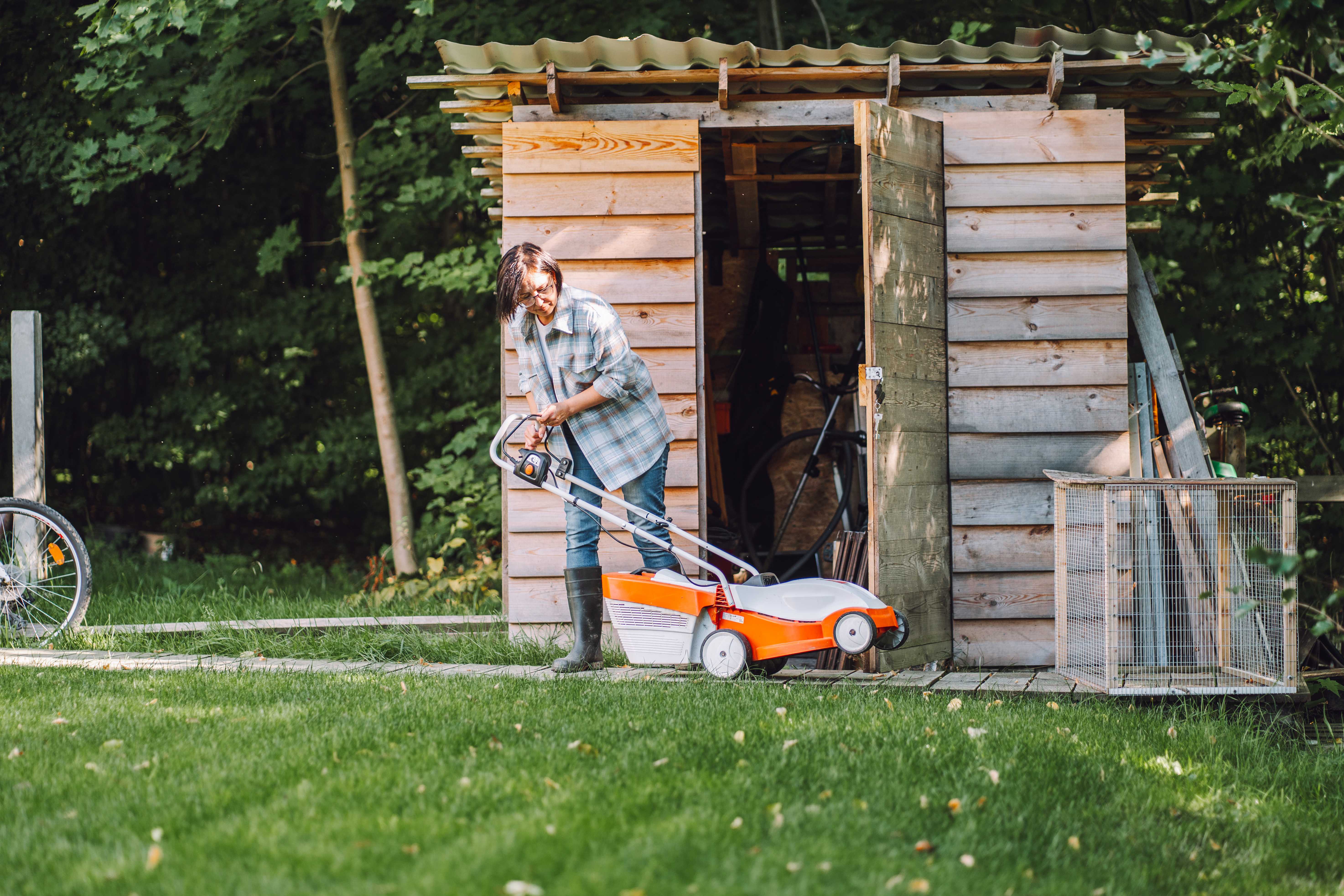 Woman putting lawnmower in shed