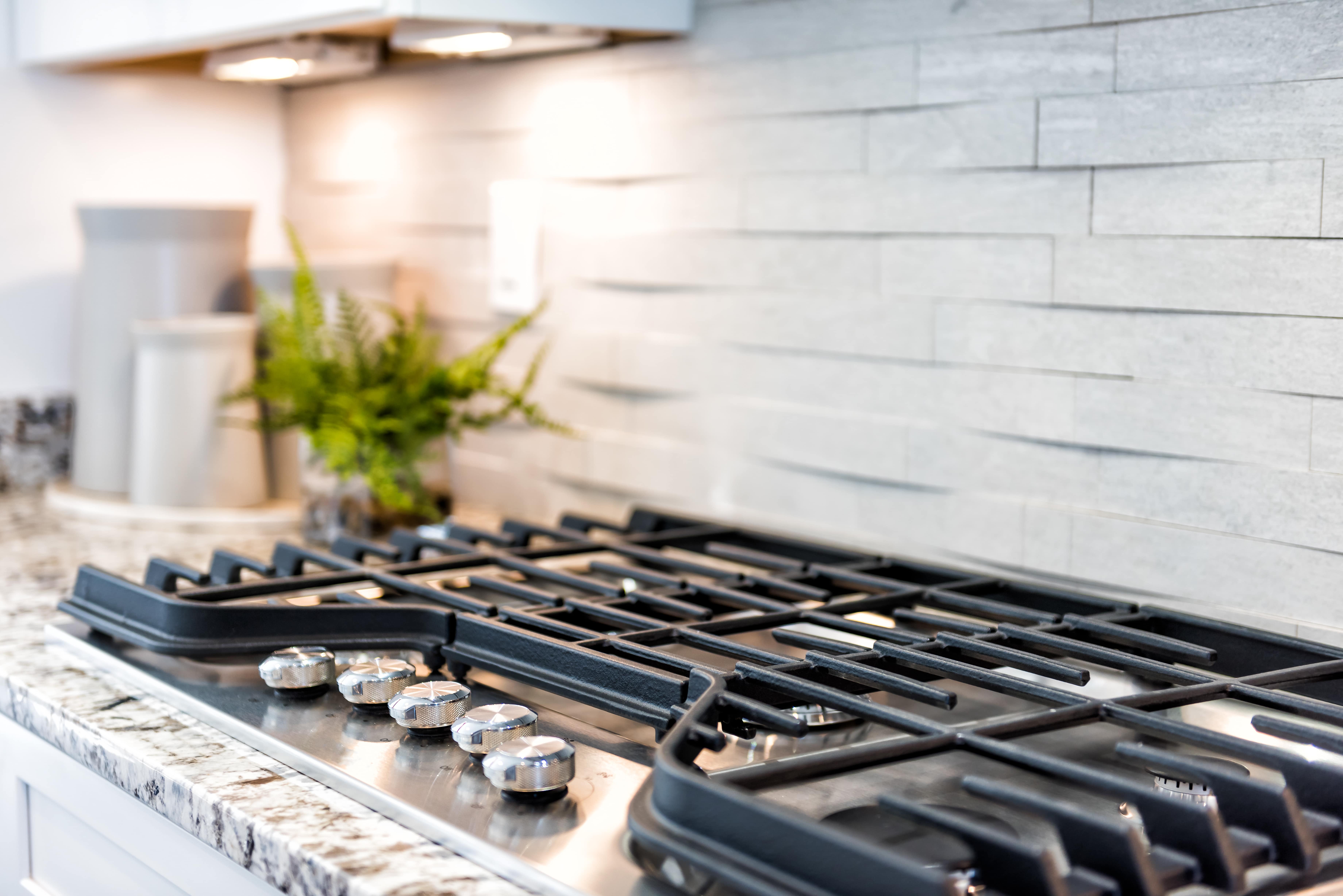 Detail of gas stove with kitchen backsplash in the background