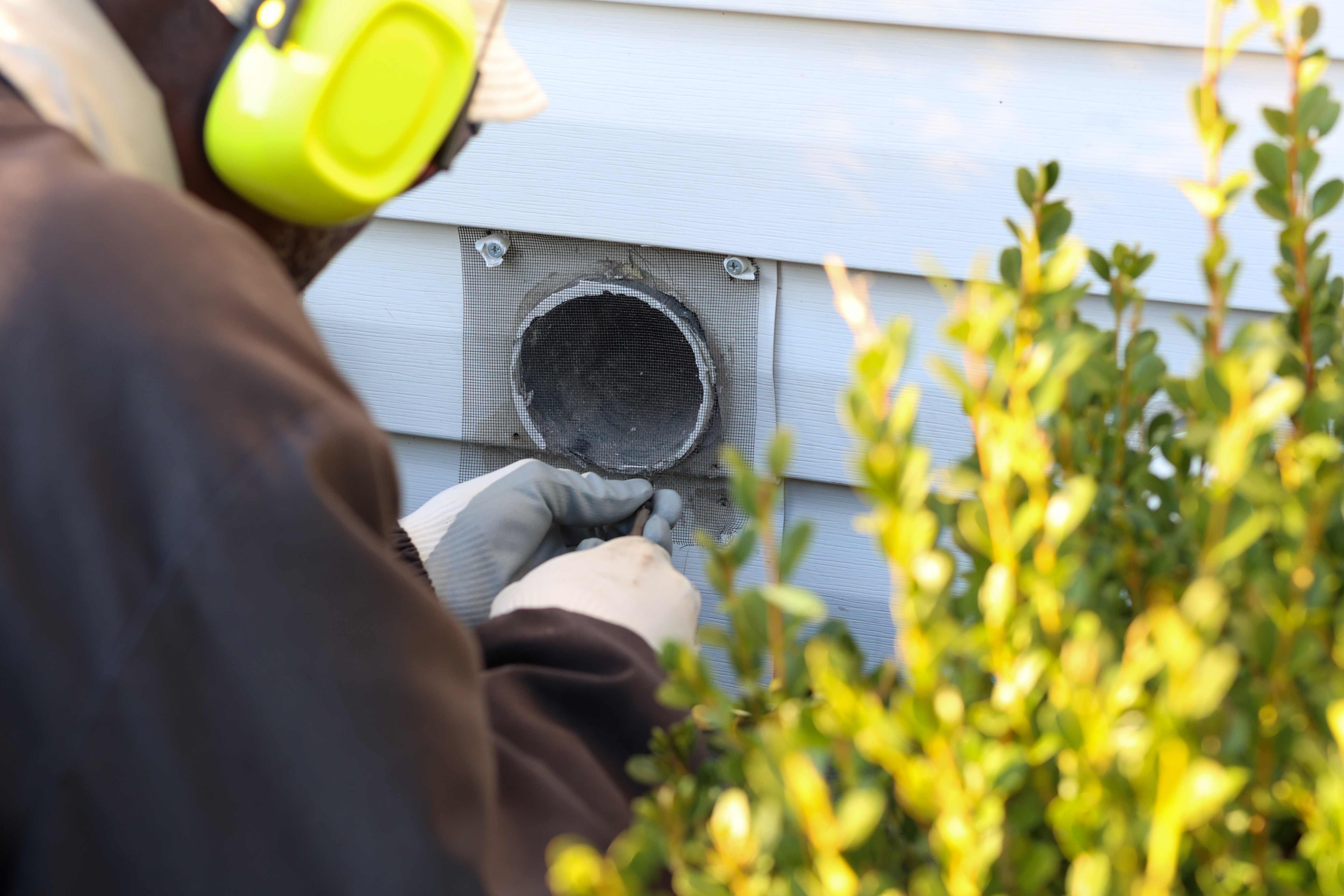 A professional inspecting a dryer vent