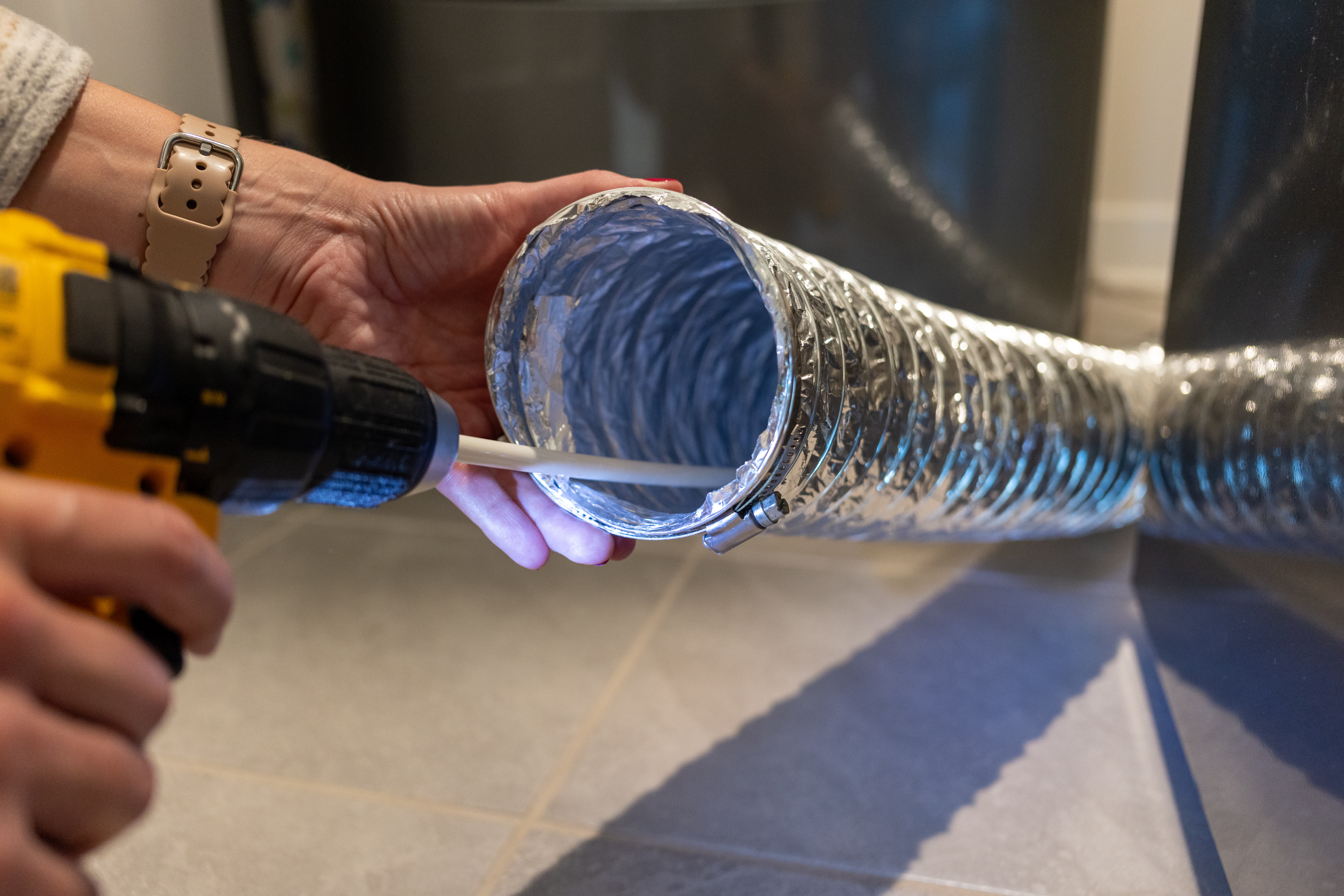 Worker cleaning dryer vent at home