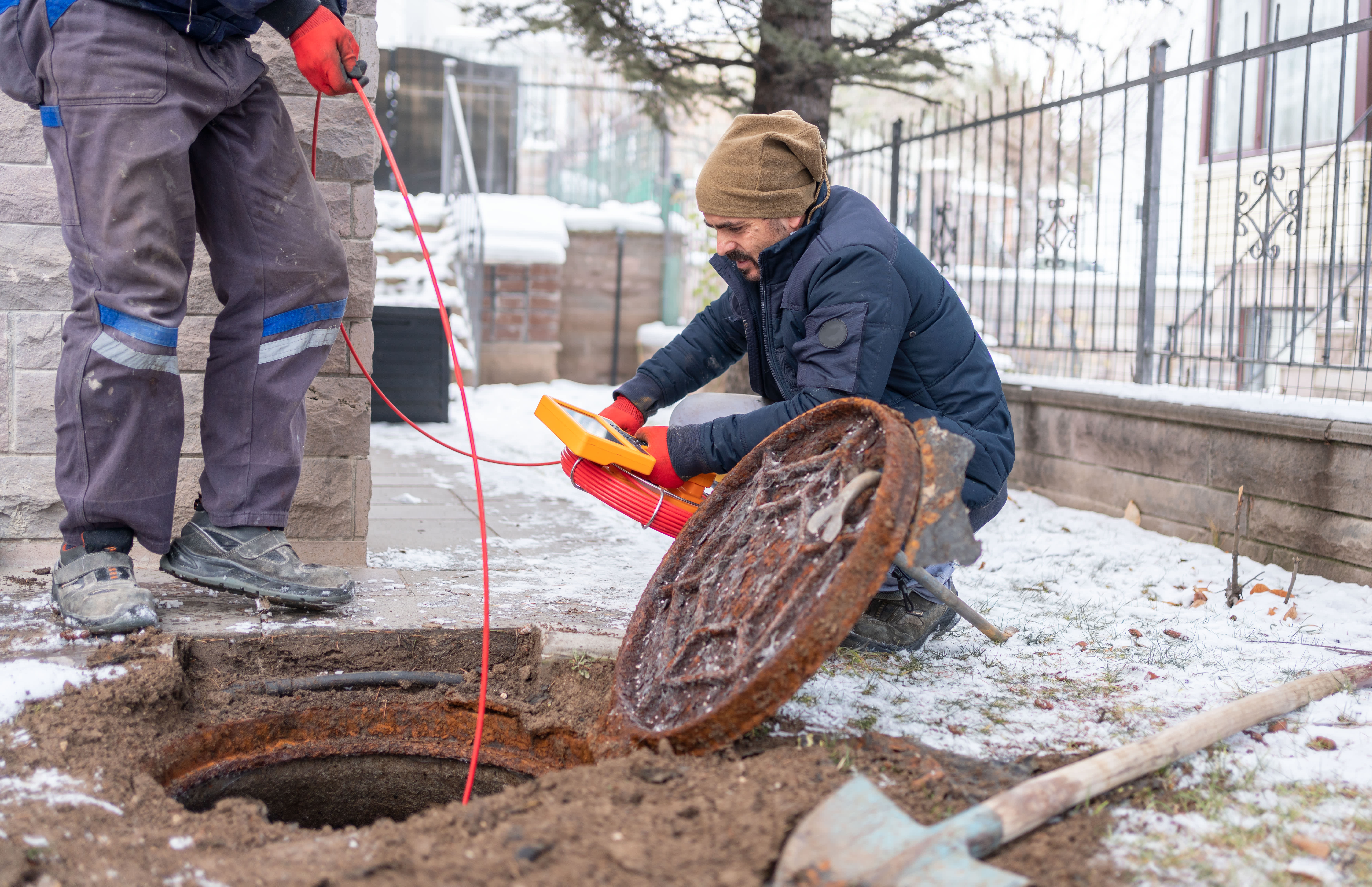 Two professionals inspecting a sewer line
