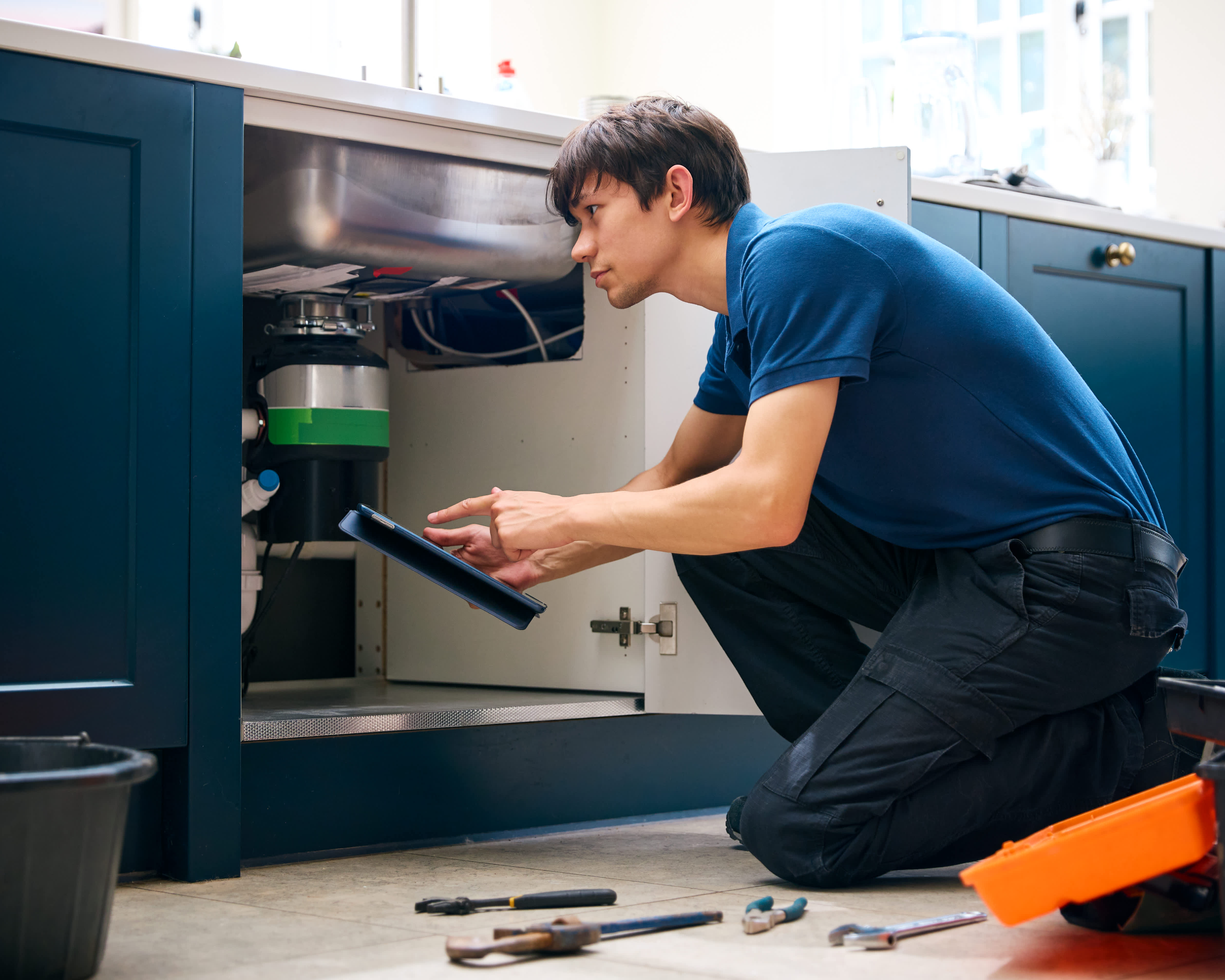 A professional cleaning a drain of a garbage disposal