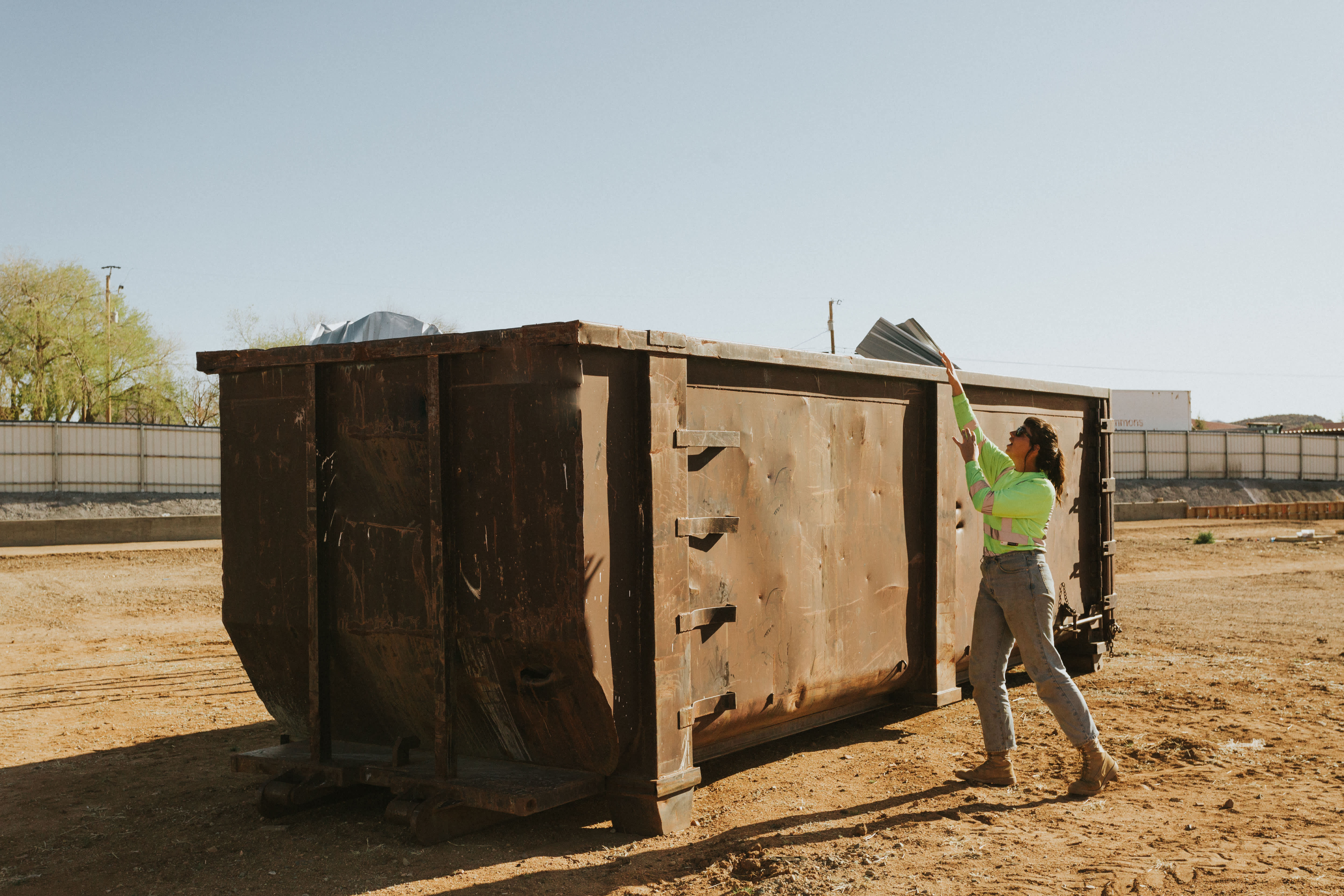 A woman throwing an item in a dumpster