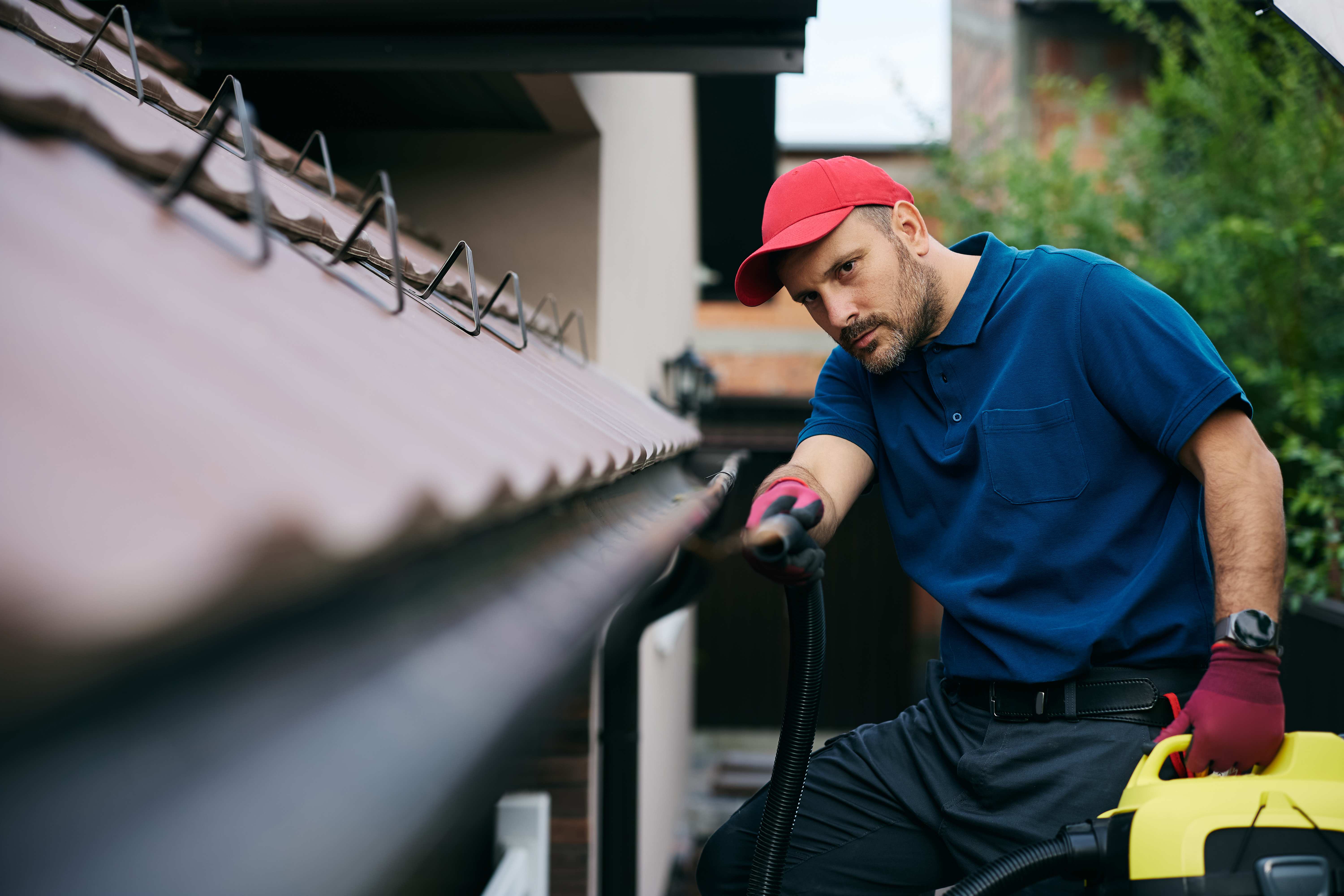 A professional cleaning the gutter of a roof