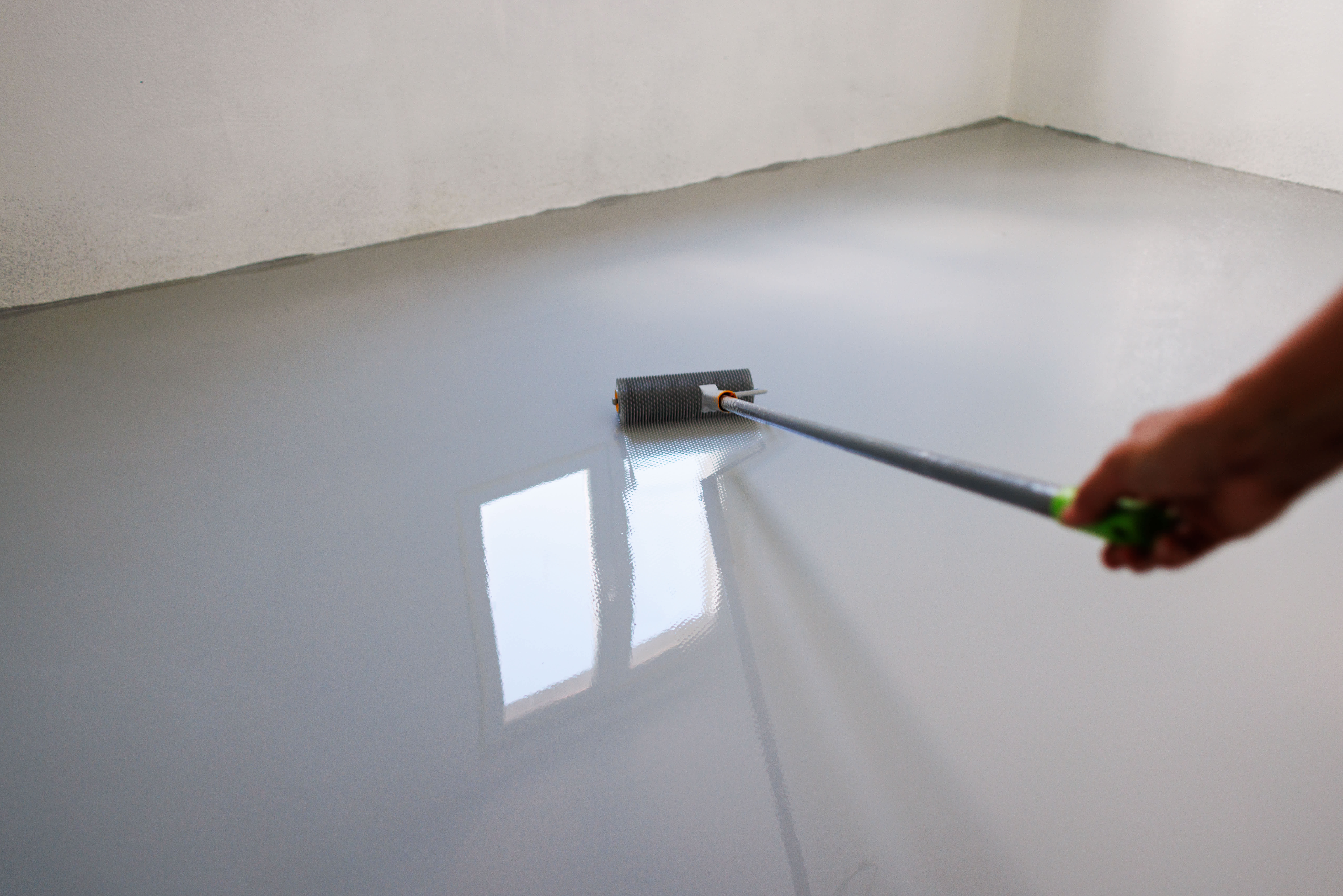 A person applying coat on a garage floor
