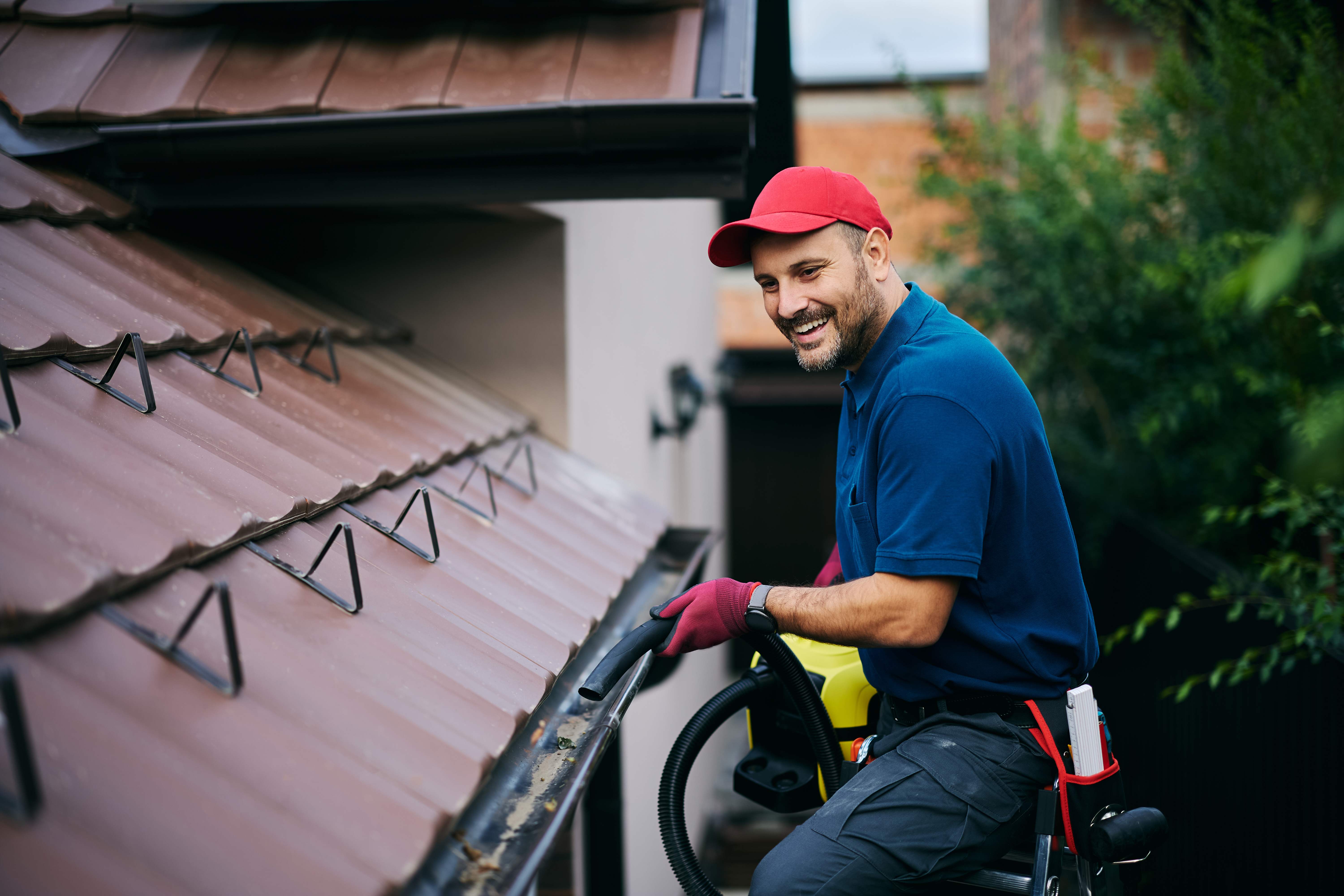 man on ladder cleaning house gutter
