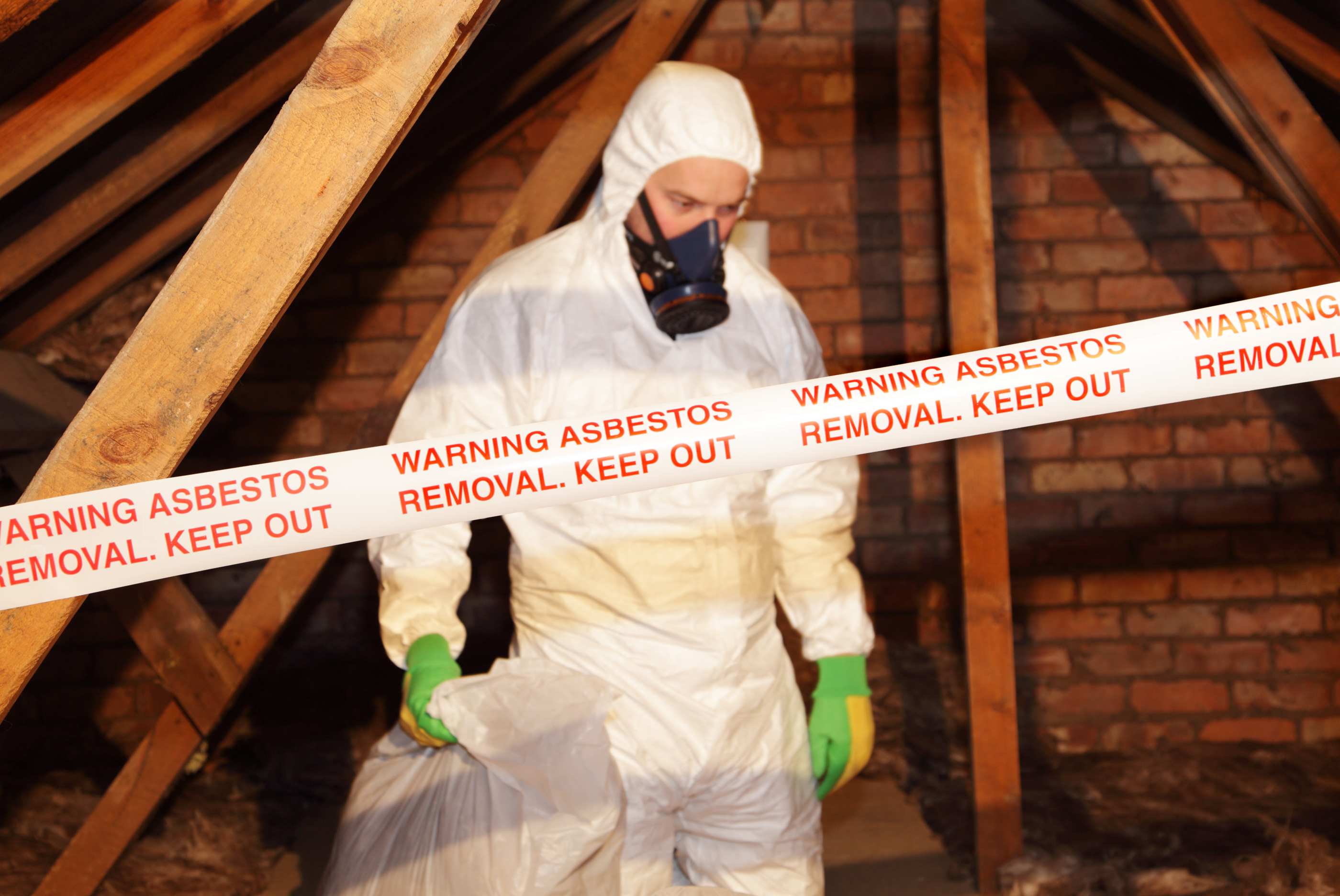 A professional removing asbestos from attic