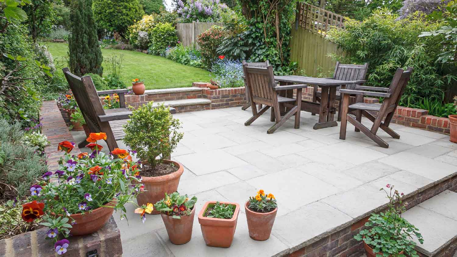 A concrete patio with wooden furniture