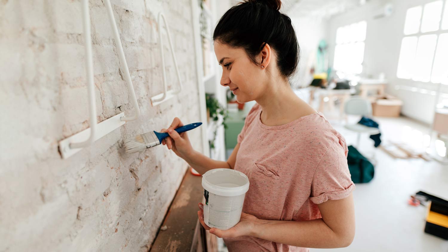 woman whitewashing apartment walls