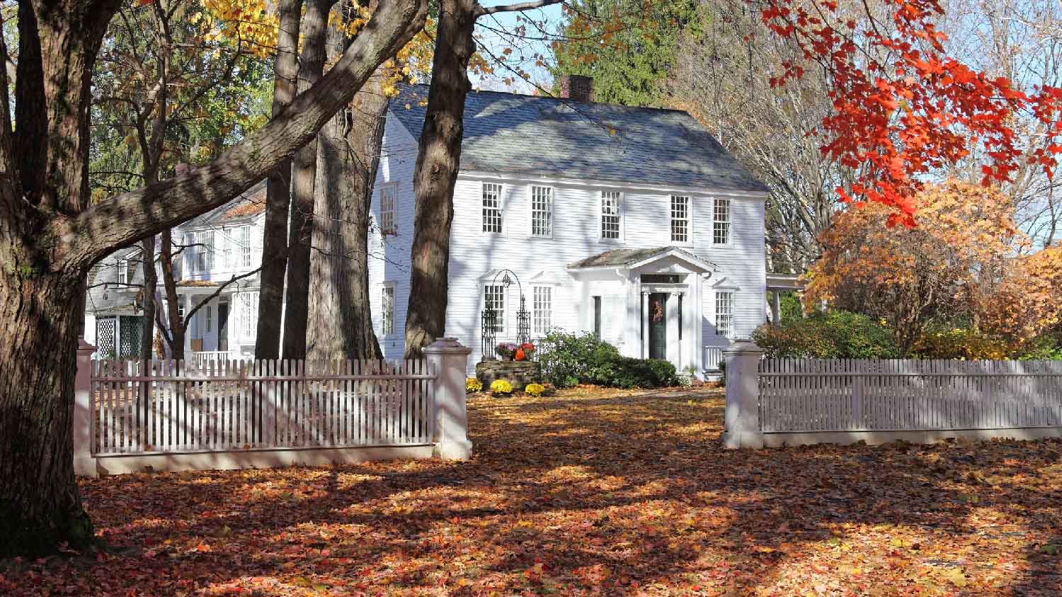A house with lots of leaves on the yard during the fall